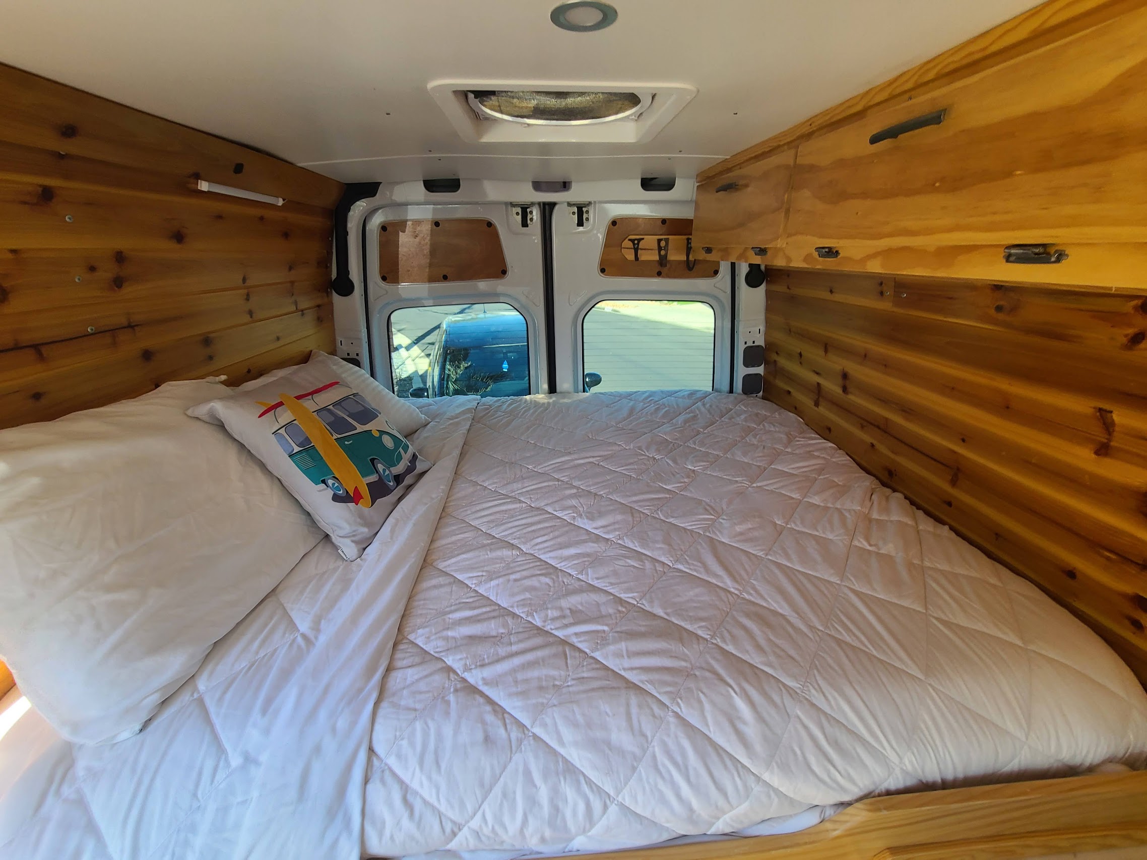 Cozy RV rental interior with a comfortable bed and wood paneling. Perfect for your next road trip adventure.. Mercedes Sprinter 2017