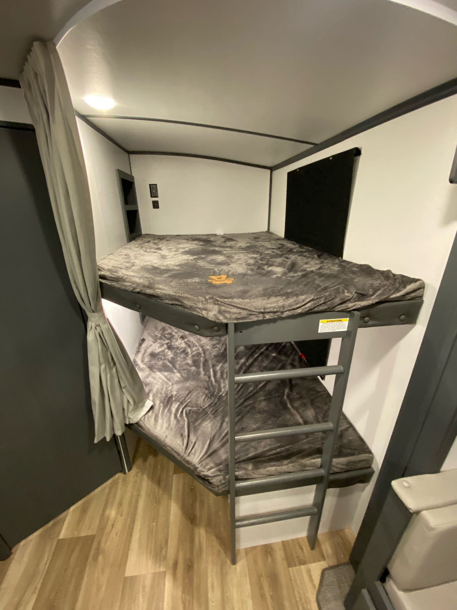 Cozy bunk beds in an RV rental interior, featuring plush grey bedding, a ladder, and a privacy curtain for travel.. Keystone RV Bullet Ultra Lite 2022