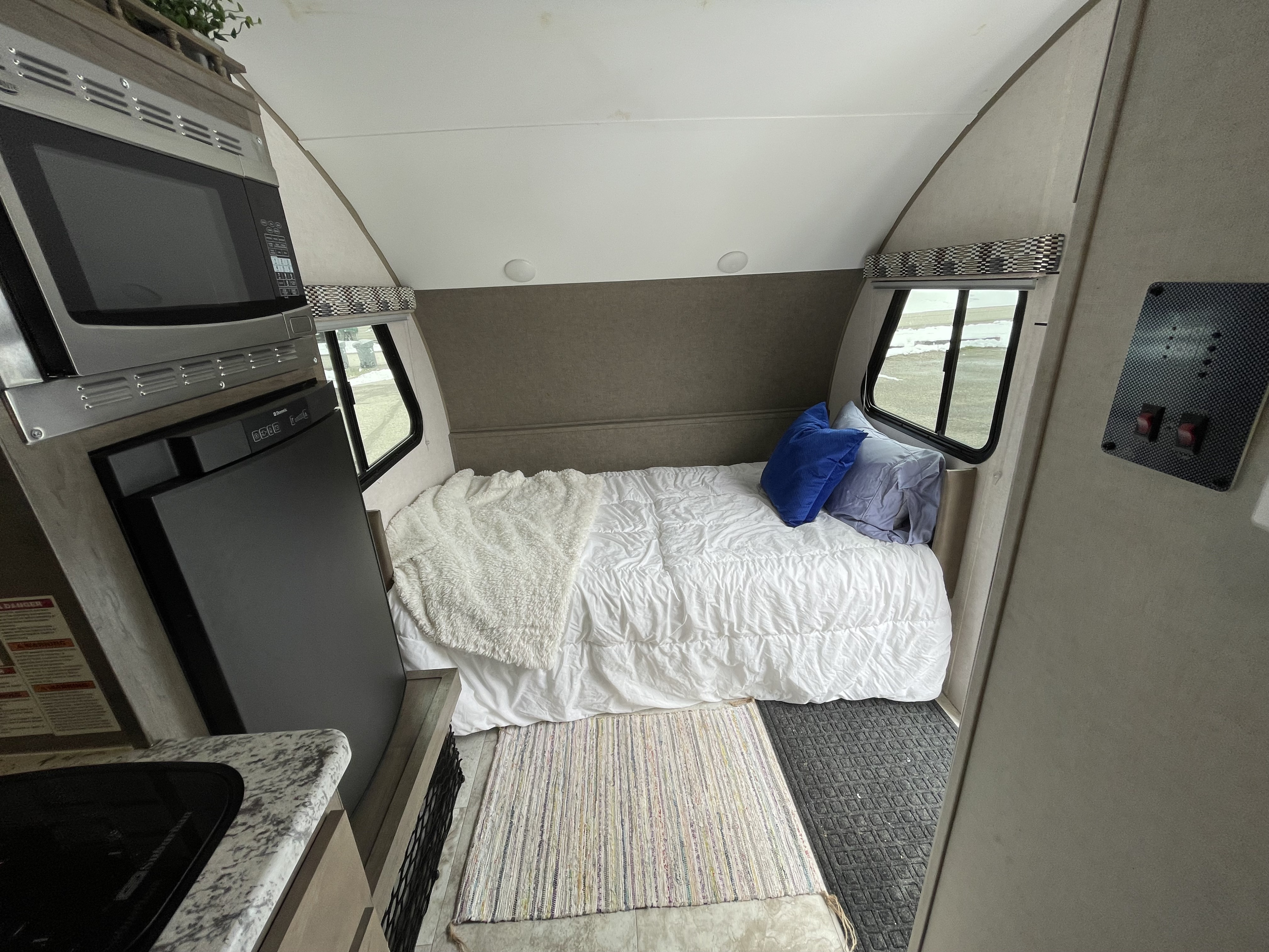 Inside this cozy RV rental: compact kitchen with microwave/fridge, comfortable bed, and windows.. R-Pod Hood River Edition 2017