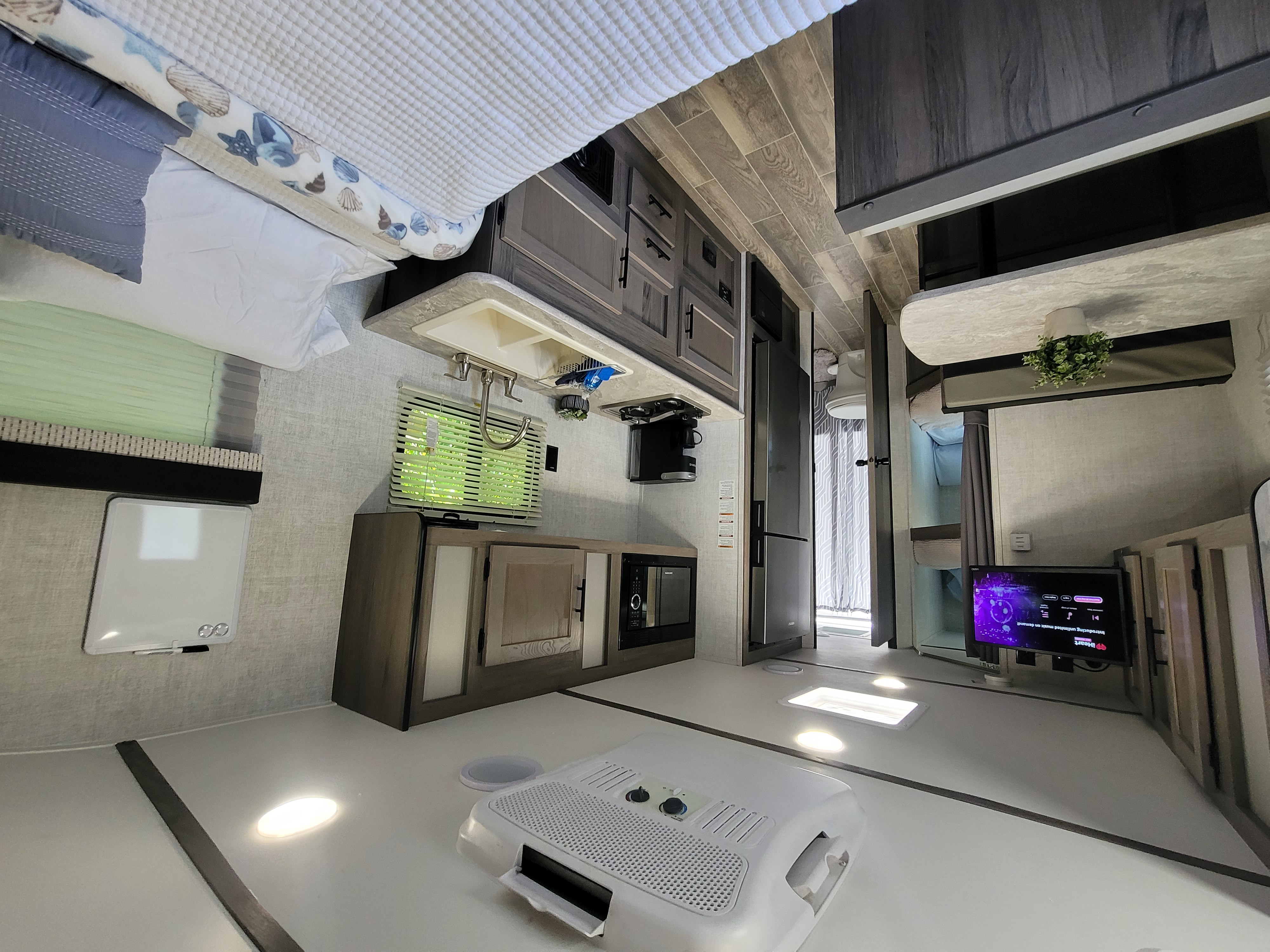 Spacious rv rental interior: bed, well-equipped kitchen (sink, microwave), dining table, TV, and compact bath.. Gulf Stream Kingsport 2022