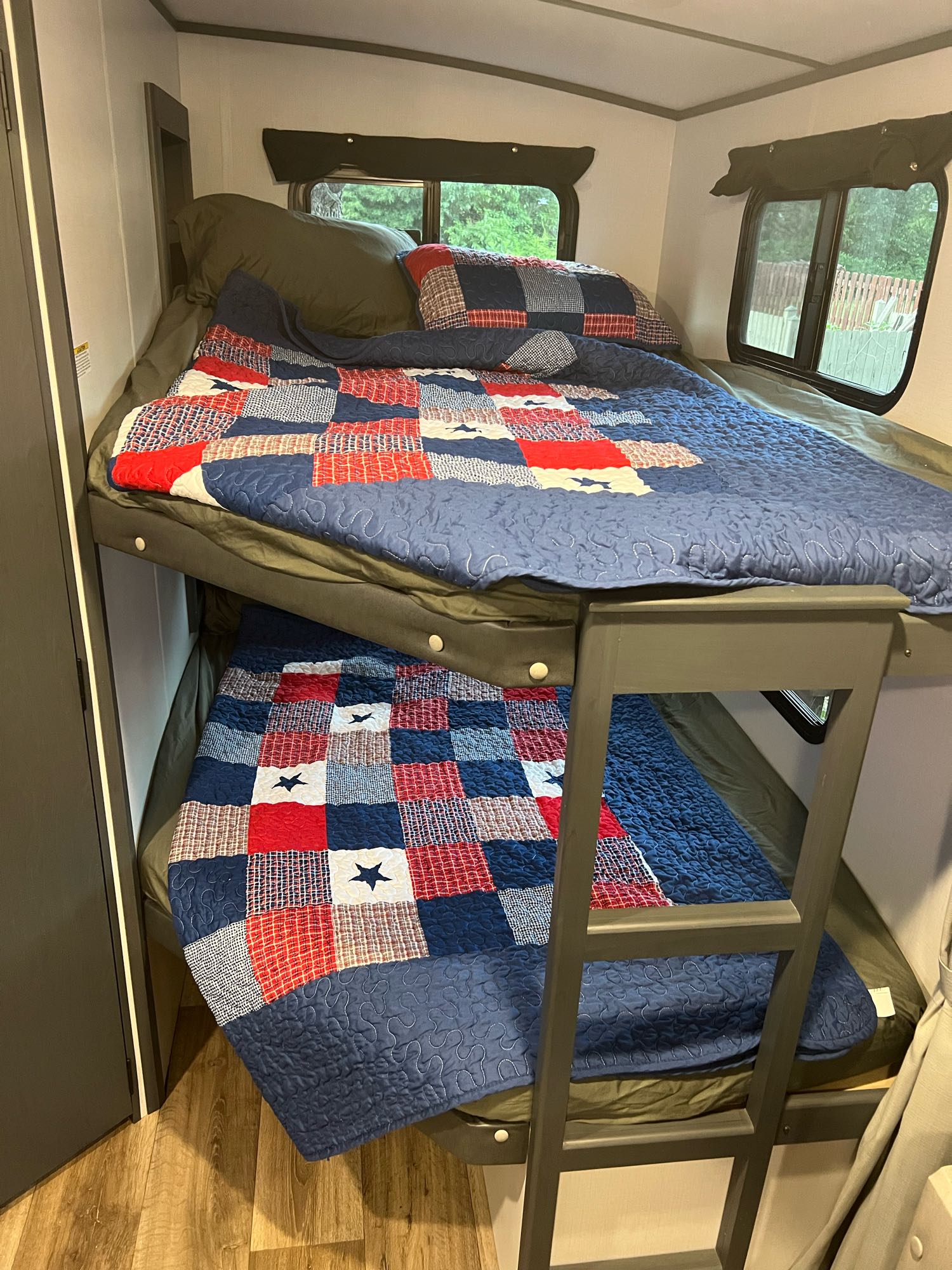 Inside an RV rental: two cozy bunk beds with patriotic red, white, and blue star quilts and a ladder.. KEYSTONE Keystone Bullet250 bhs 2022