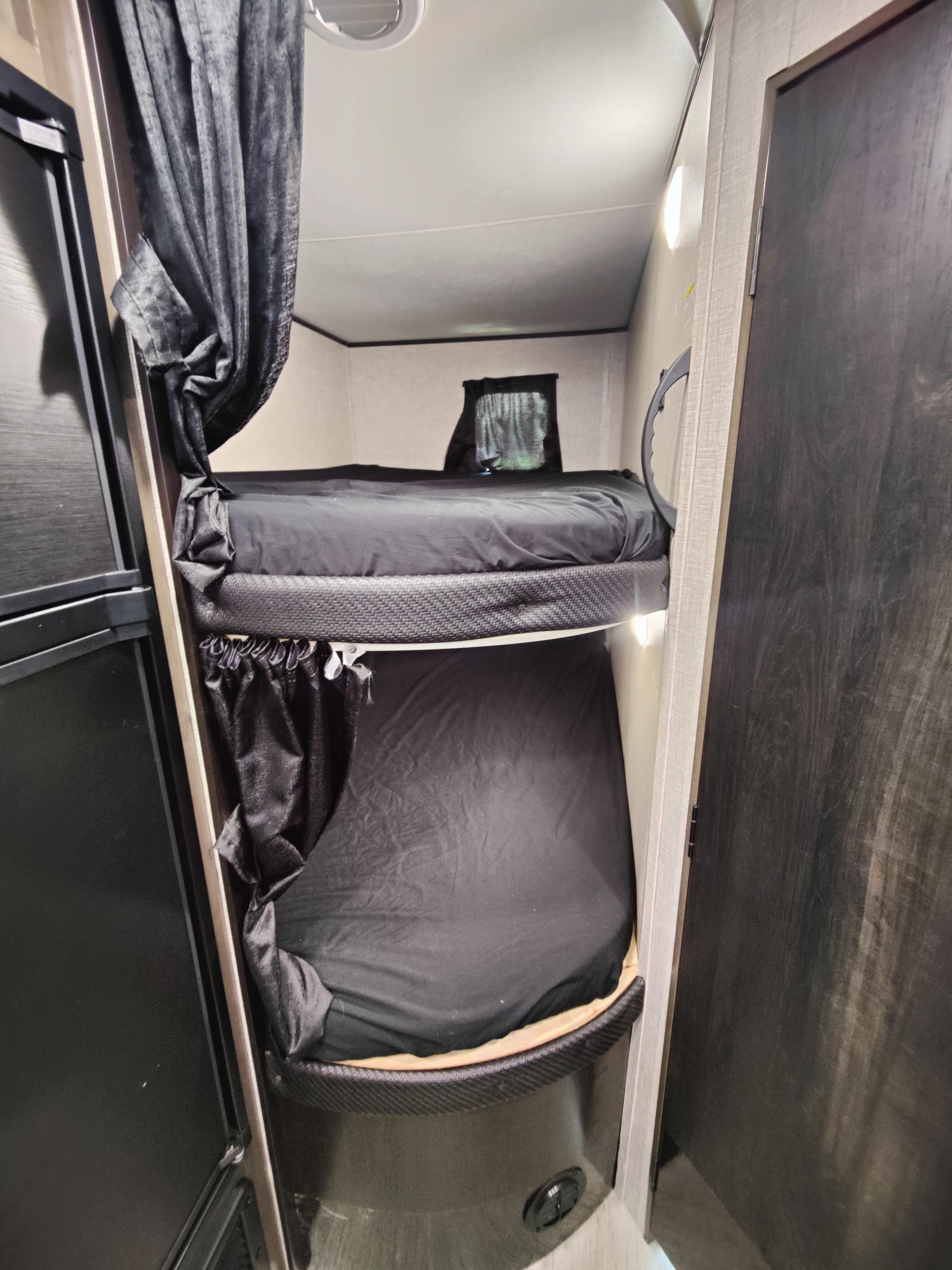 RV rental bunk beds: A compact sleeping area with black bedding, privacy curtains, and a window.. Jayco Jay Flight SLX 2022