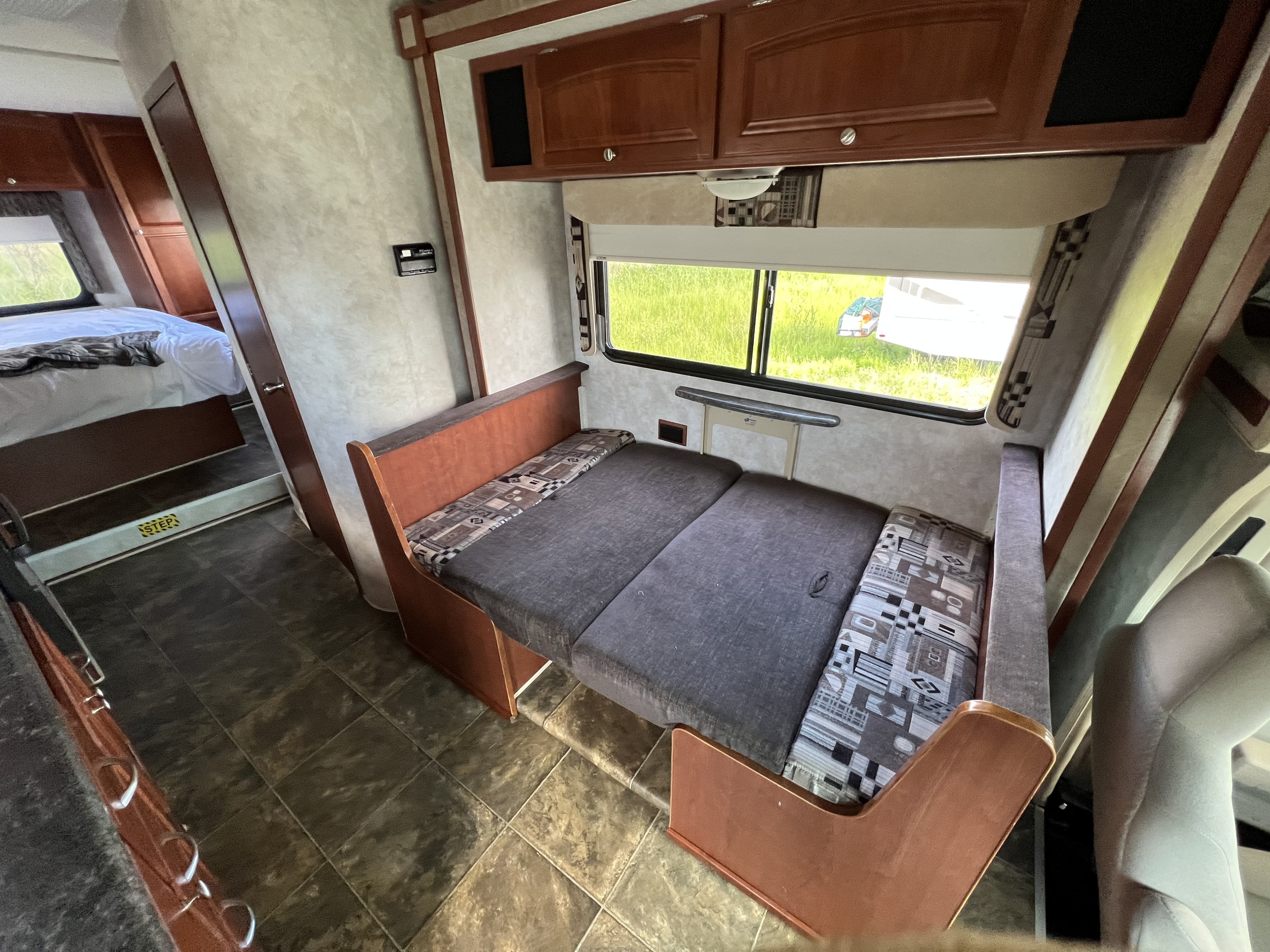 Inside an RV rental: a versatile living area featuring a convertible dinette bed and a peek into the cozy bedroom.. Winnebago Chalet 2013