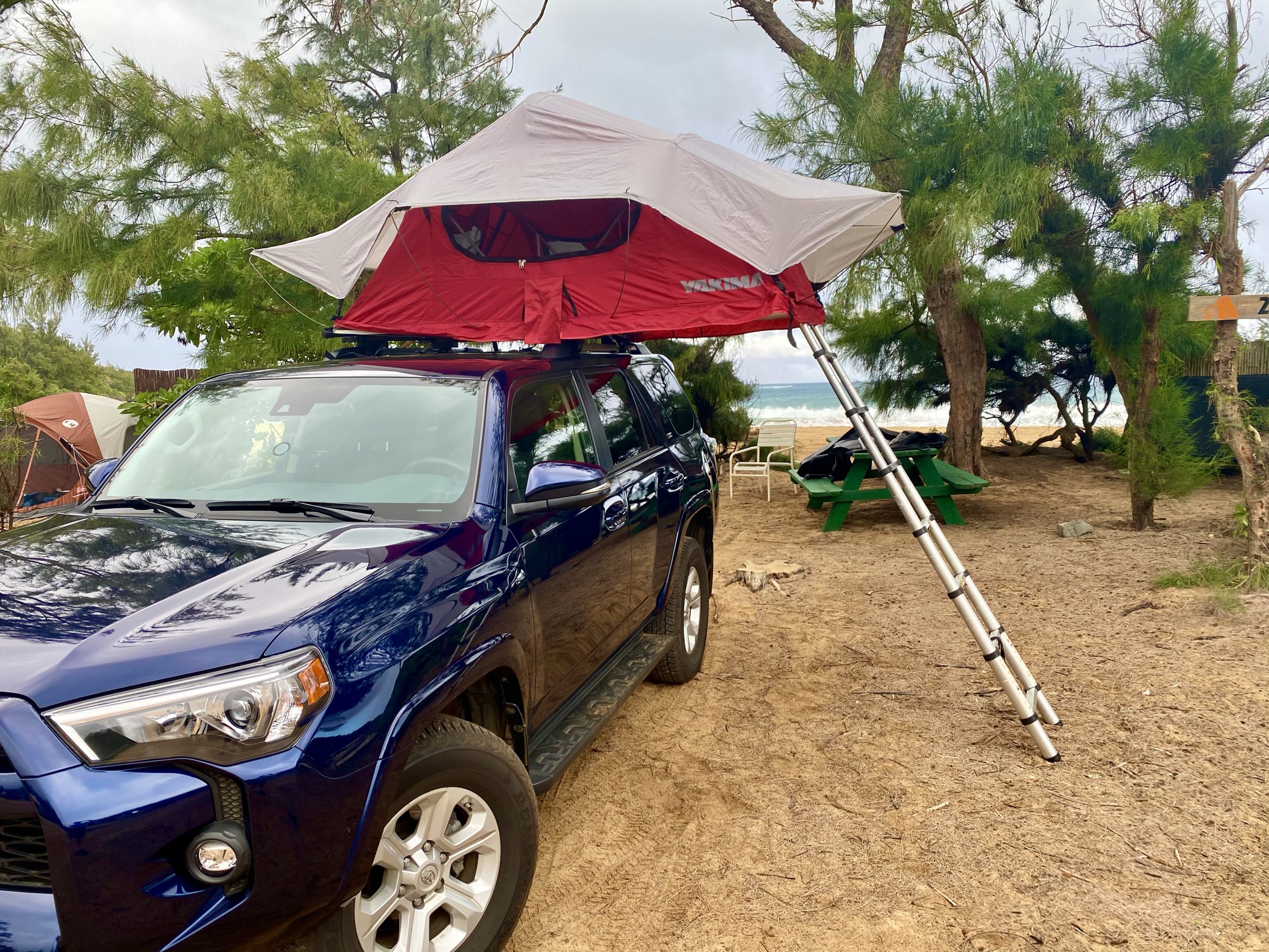 Beachside RV rental: blue SUV with rooftop tent deployed for sandy camping by the ocean.. Other Other 2021