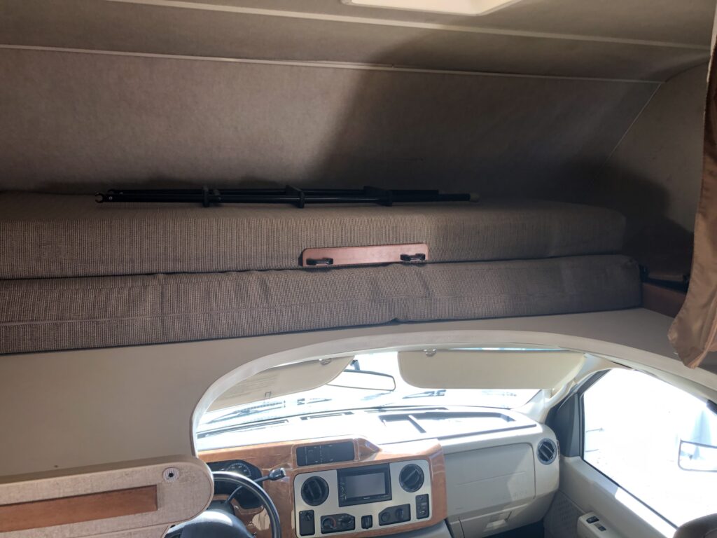 Inside an RV rental: The cab-over bunk bed with cushions, positioned above the vehicle's cockpit. Ideal for extra sleeping.. Winnebago Chalet 2014