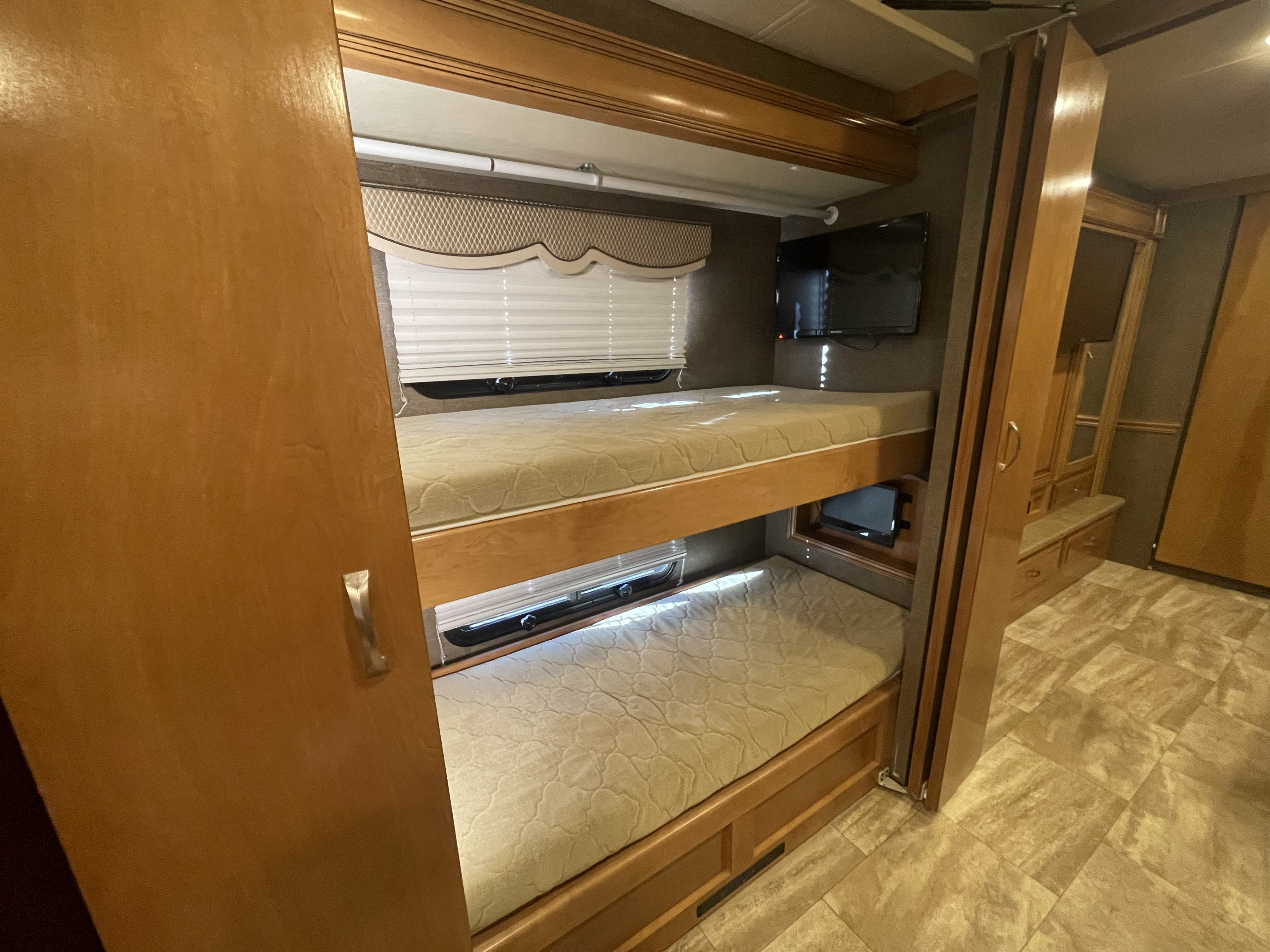 RV rental interior featuring two comfortable bunk beds with mattresses, windows, and an entertainment TV.. Thor Challenger 2017