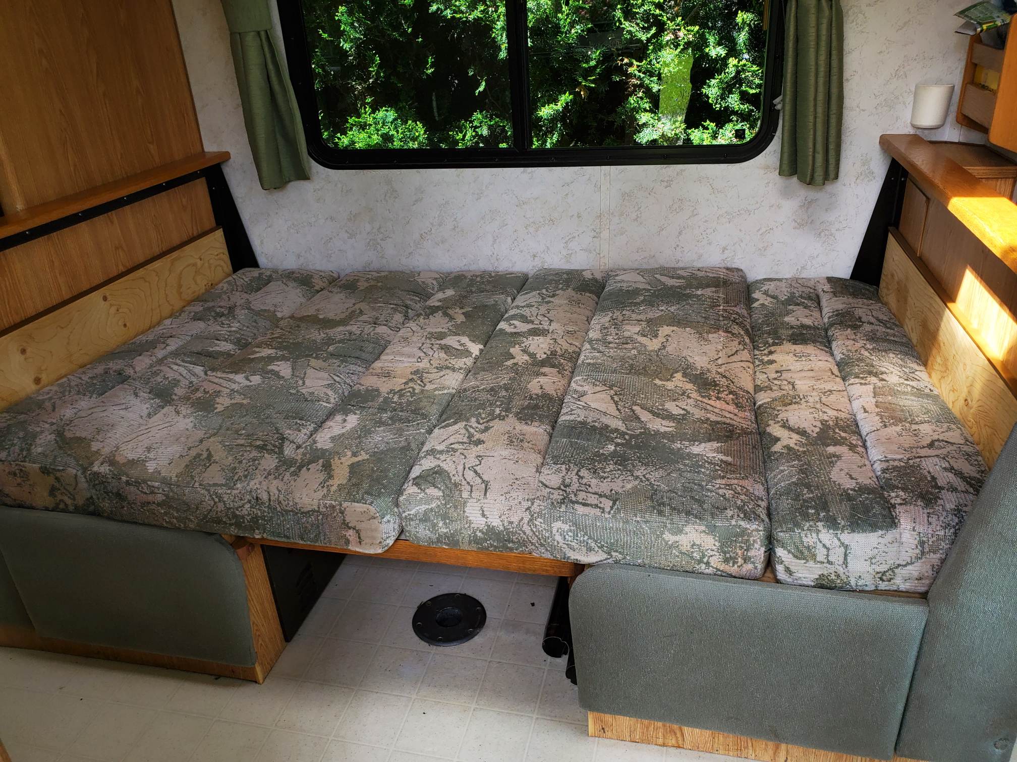 Experience comfort in this RV rental. Interior shot shows a bed/bench with patterned cushions, window view, and wood accents.. Travelaire Travelaire Motorhome 2000