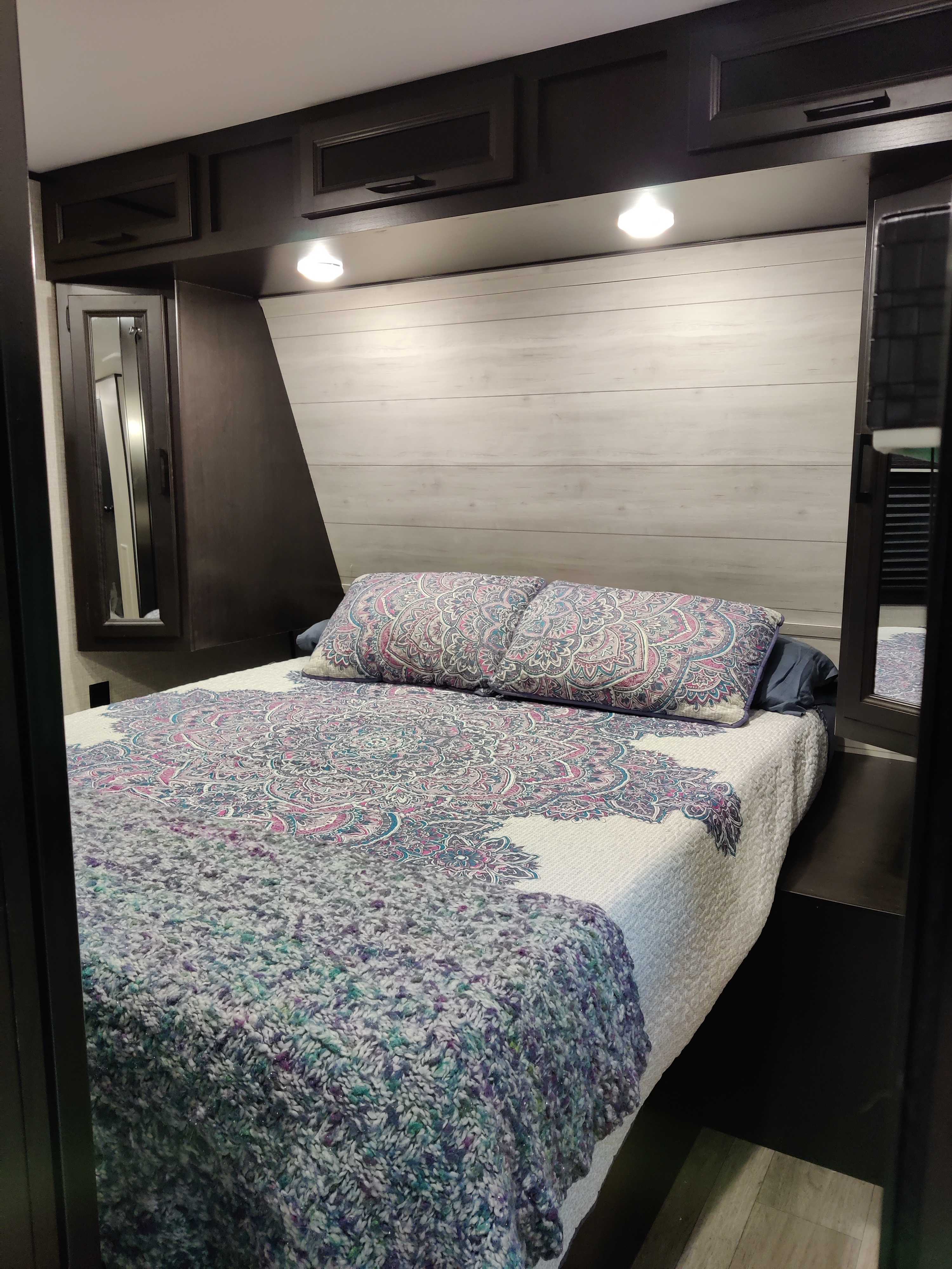 Cozy RV rental bedroom with patterned bedding, modern dark wood cabinets, and light wood accent wall.. Jayco Jay Flight 32BHDS 2022