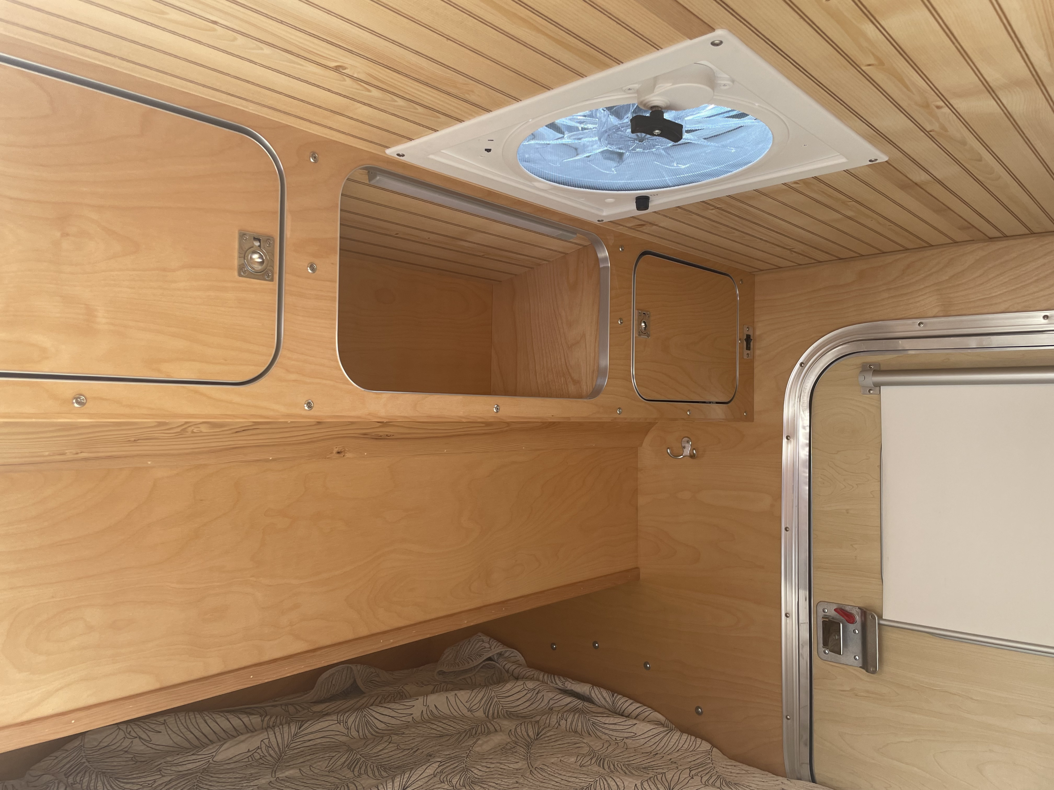 Inside an RV rental: a warm wood-paneled interior with built-in storage, a ceiling fan, and cozy bedding, ready for adventure.. Other Other 2019