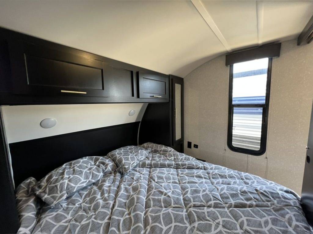 Cozy RV rental bedroom with black cabinets, a comfy bed, and a window. Perfect for your next travel adventure!. Forest River Cherokee Grey Wolf 2022