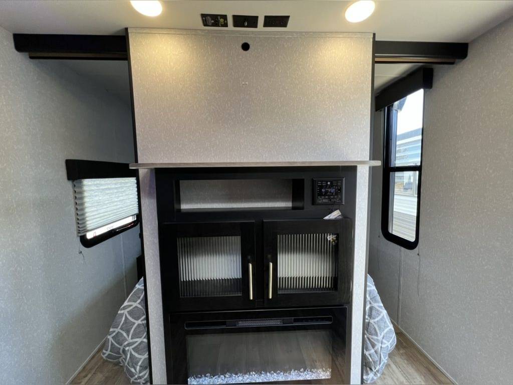 RV rental interior: slide-out bedroom with modern fireplace, entertainment unit, and bright windows.. Forest River Cherokee Grey Wolf 2022
