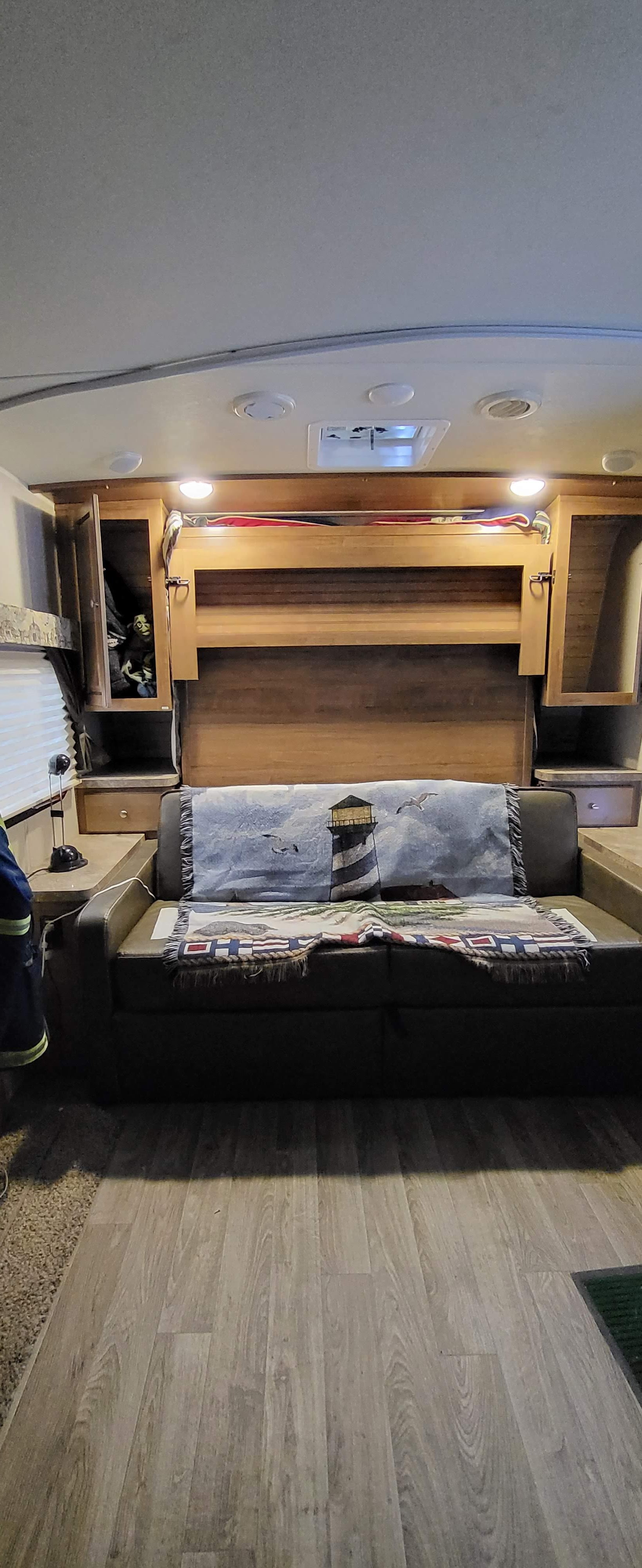 RV rental interior featuring a versatile sofa-bed, overhead cabinets, and wood-look flooring.. Forest River Flagstaff Micro Lite 2018