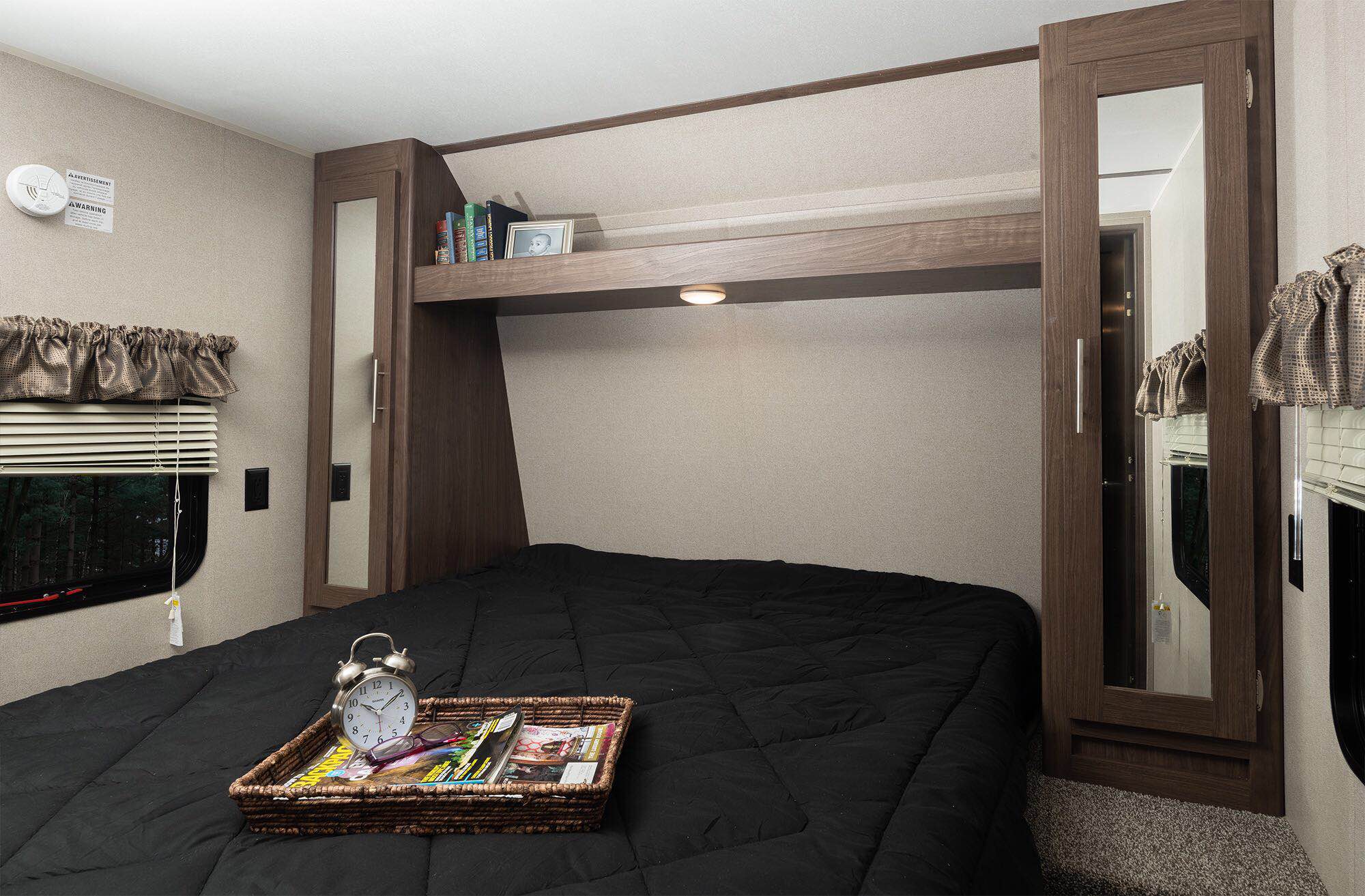 Inside this RV rental bedroom: a cozy bed, window with blinds, an alarm clock on a tray, and practical mirrored storage.. Keystone RV Hideout LHS 2019