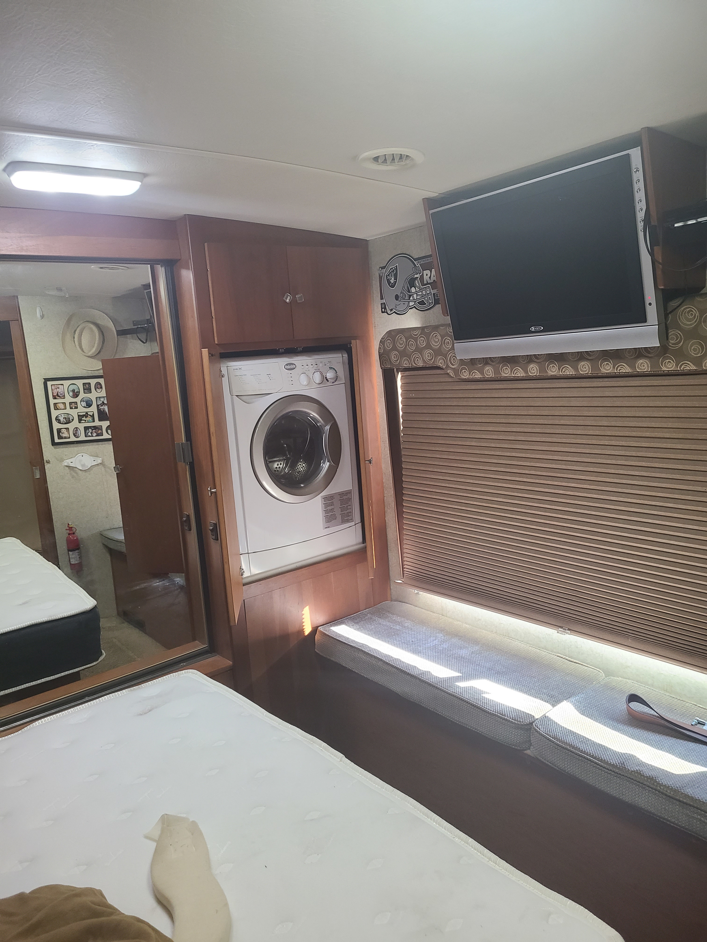 RV rental interior featuring a washer/dryer, mounted TV, built-in seating, and twin mattresses for compact living.. Itasca Meridian 2008
