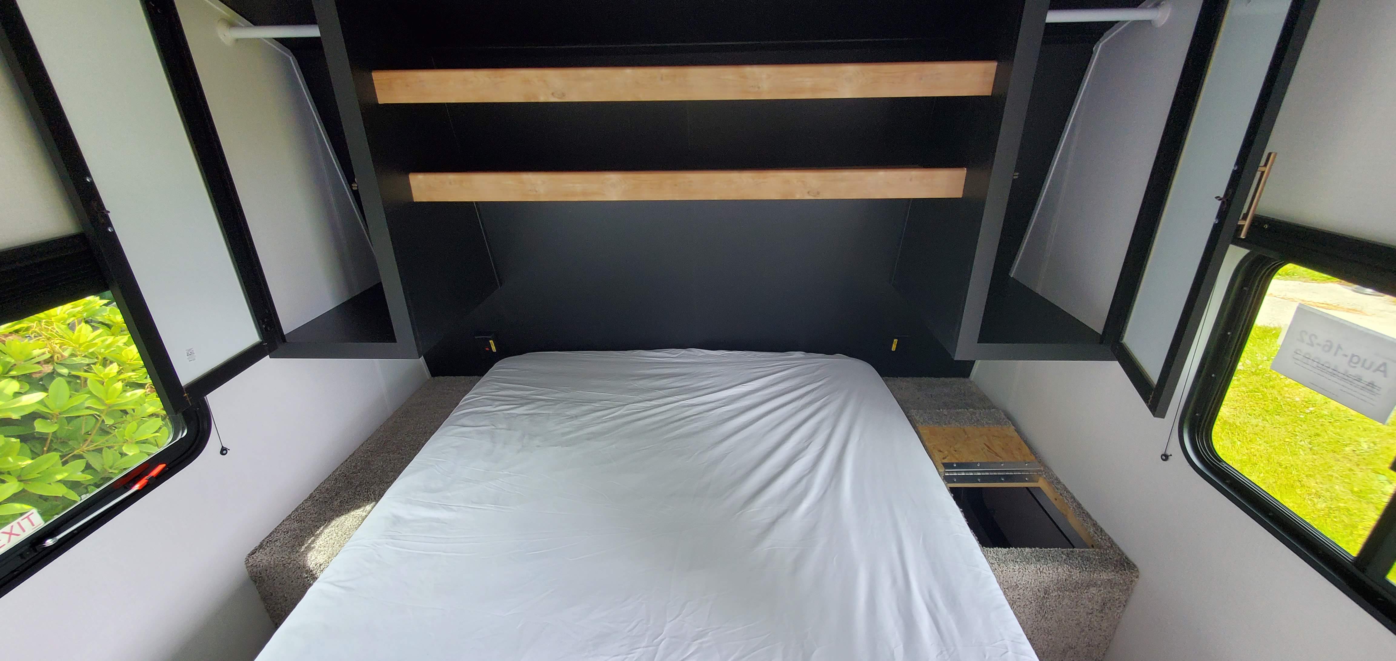 RV rental bedroom: a compact sleeping area with a bed, built-in shelves, and large side windows for light.. Keystone RV Springdale 2022