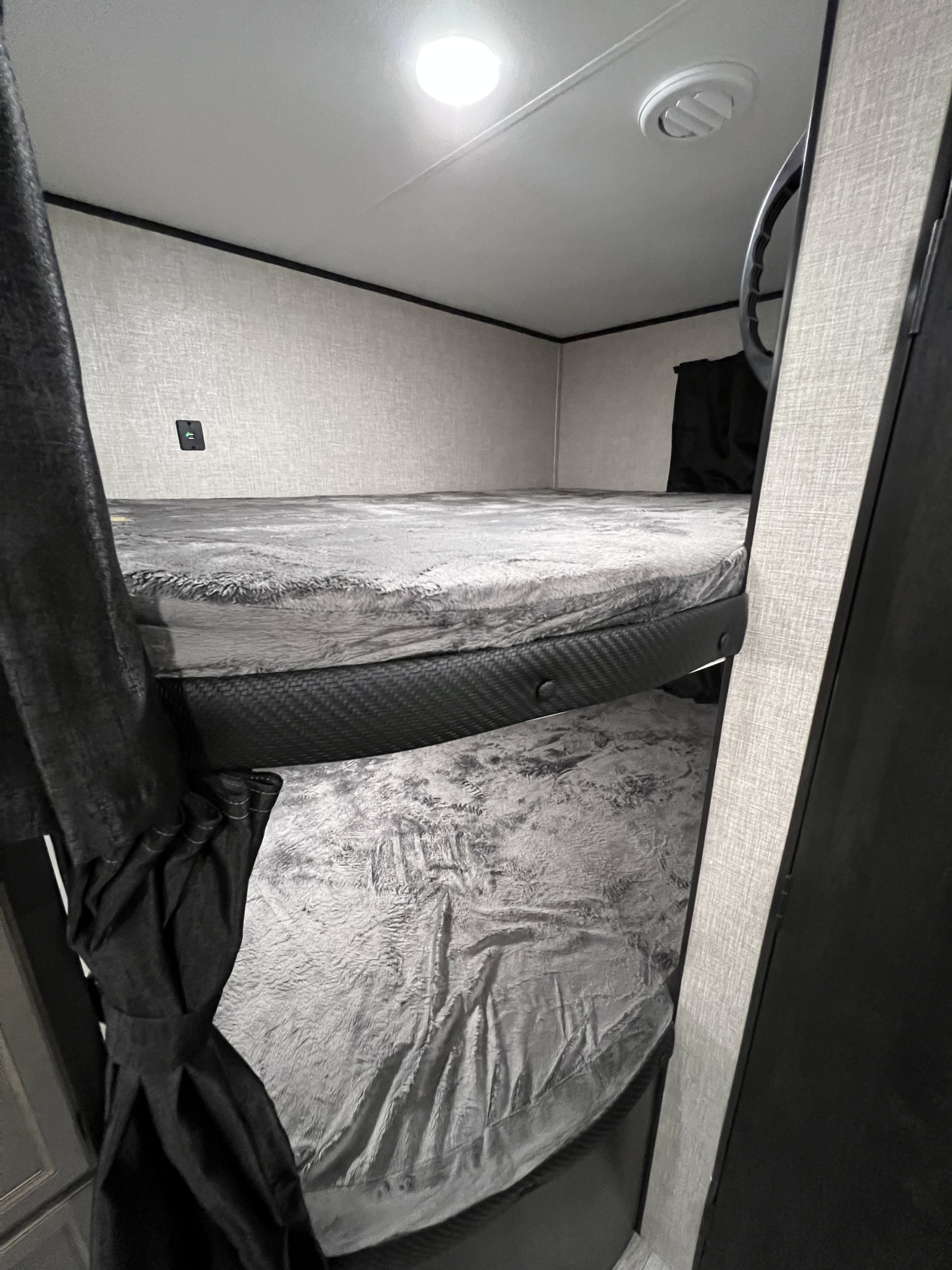 Cozy RV rental sleeping area with two bunk beds, fluffy gray blankets, ceiling light, and air vent visible.. Jayco Jay Flight 2022