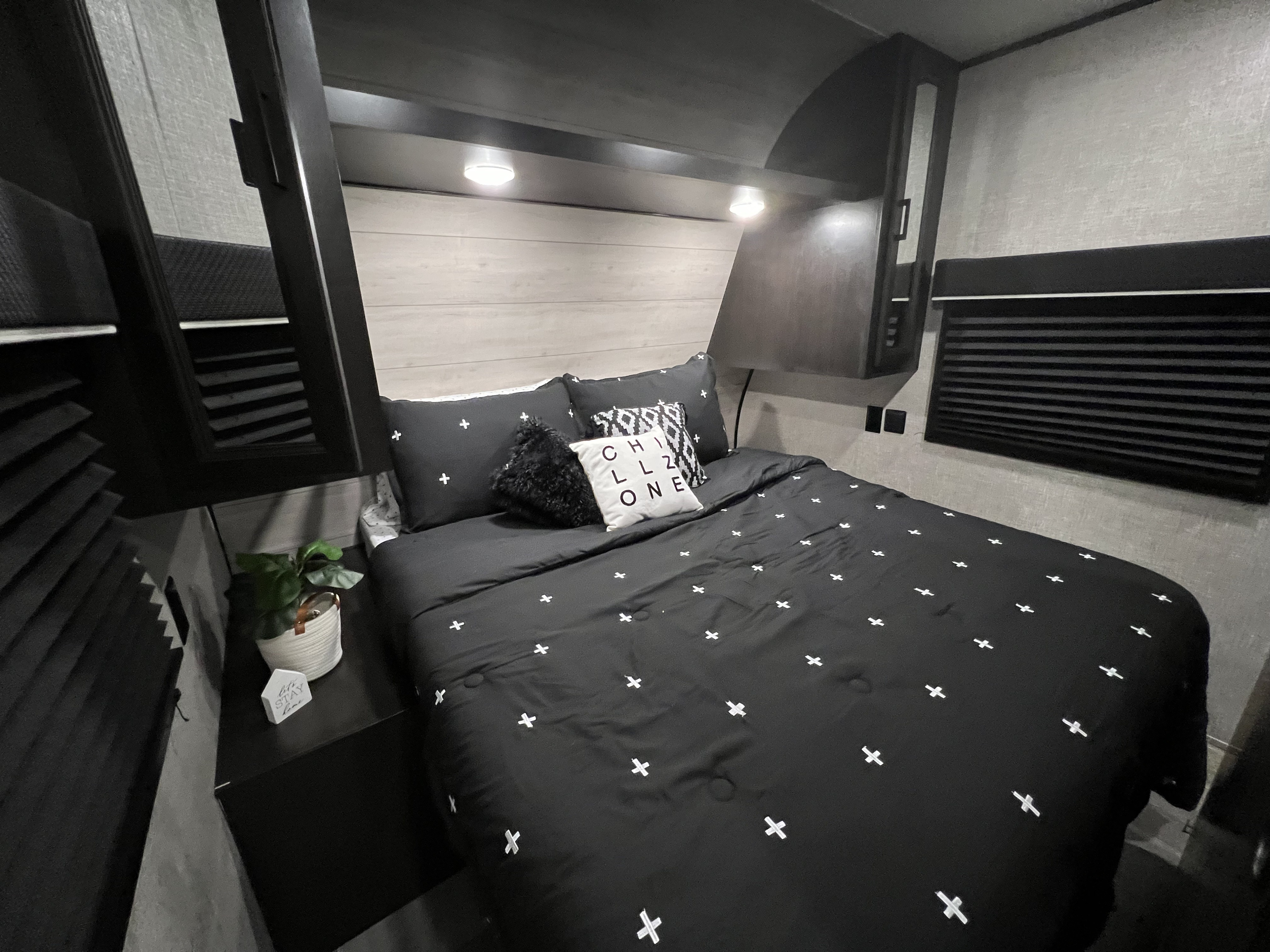 Cozy, modern RV rental bedroom with black and white bedding, pillows, overhead lights, and practical storage, perfect for travel.. Jayco Jay Flight 2022