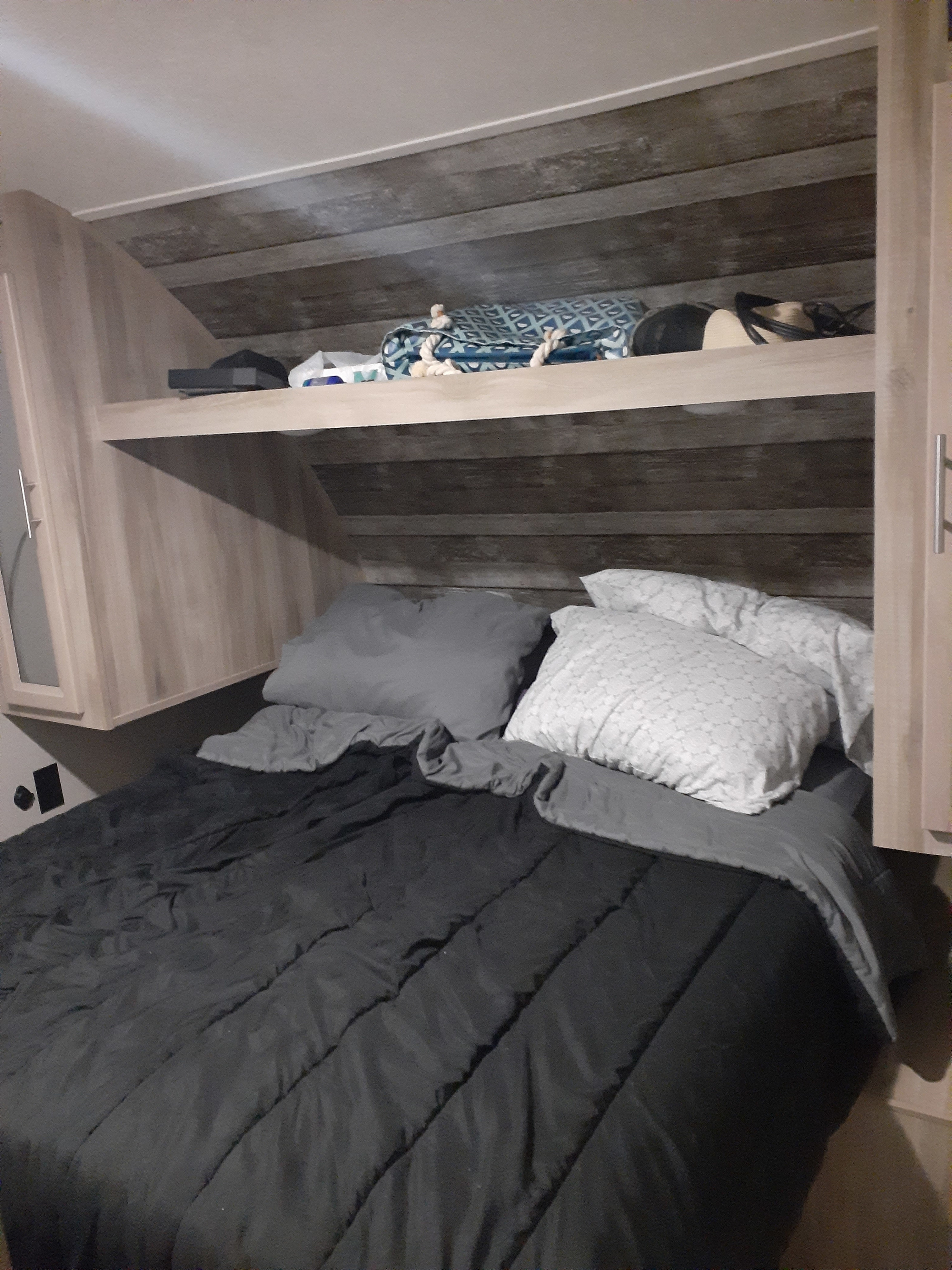Cozy RV rental bedroom features a comfy bed with dark comforter, patterned pillows, and convenient overhead storage.. Forest River Coachmen Catalina Summit 2020