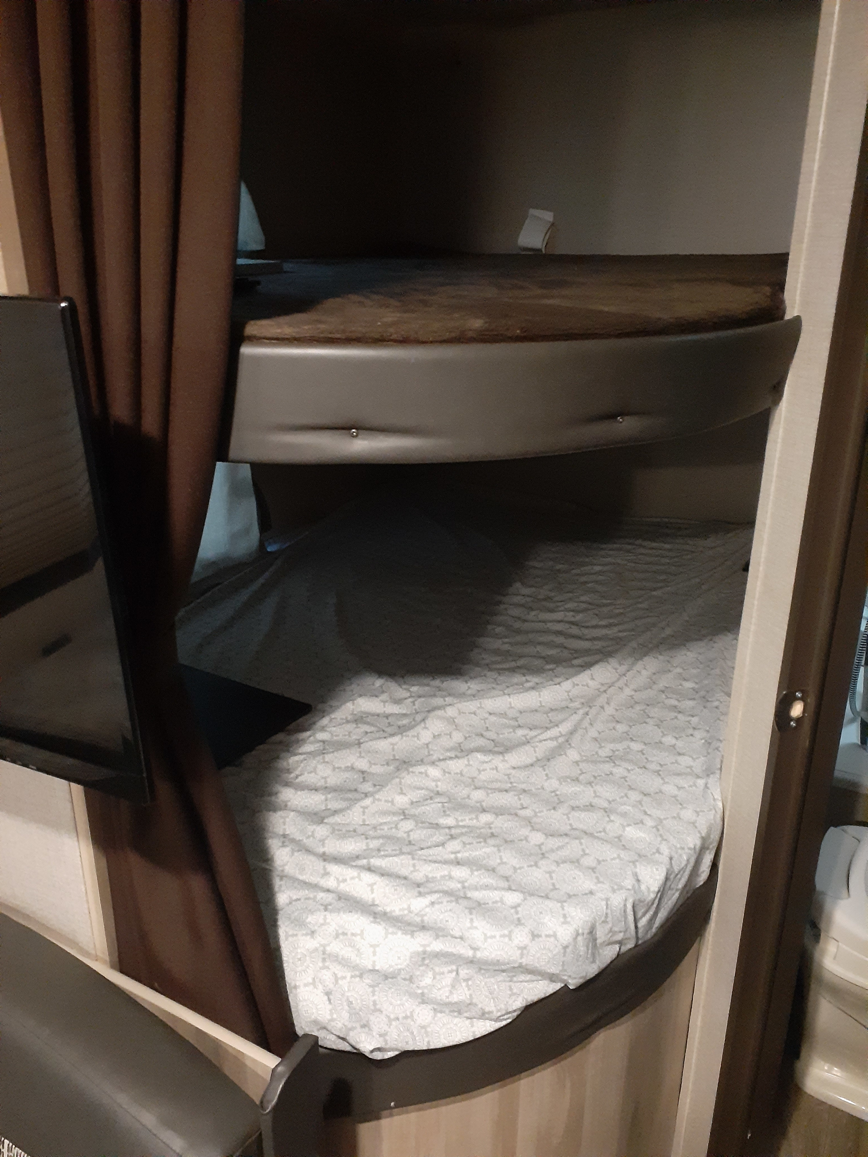 Cozy RV rental interior featuring two bunk beds with a TV mounted by the bottom bunk, offering compact sleeping space.. Forest River Coachmen Catalina Summit 2020