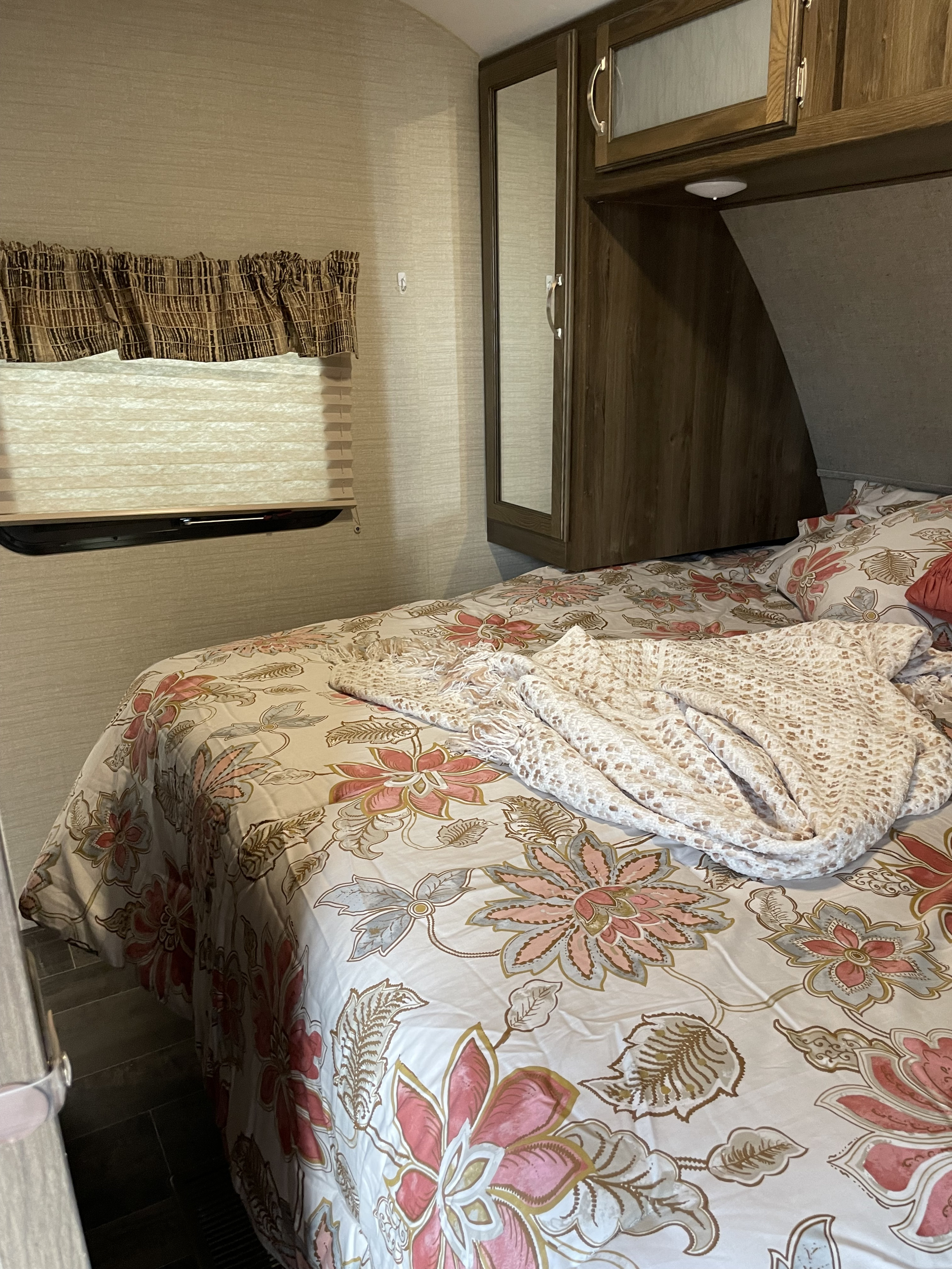 Comfortable RV rental bedroom featuring floral bedding, a window with shade, and built-in mirrored cabinetry.. Keystone RV Bullet-308BHS 2018