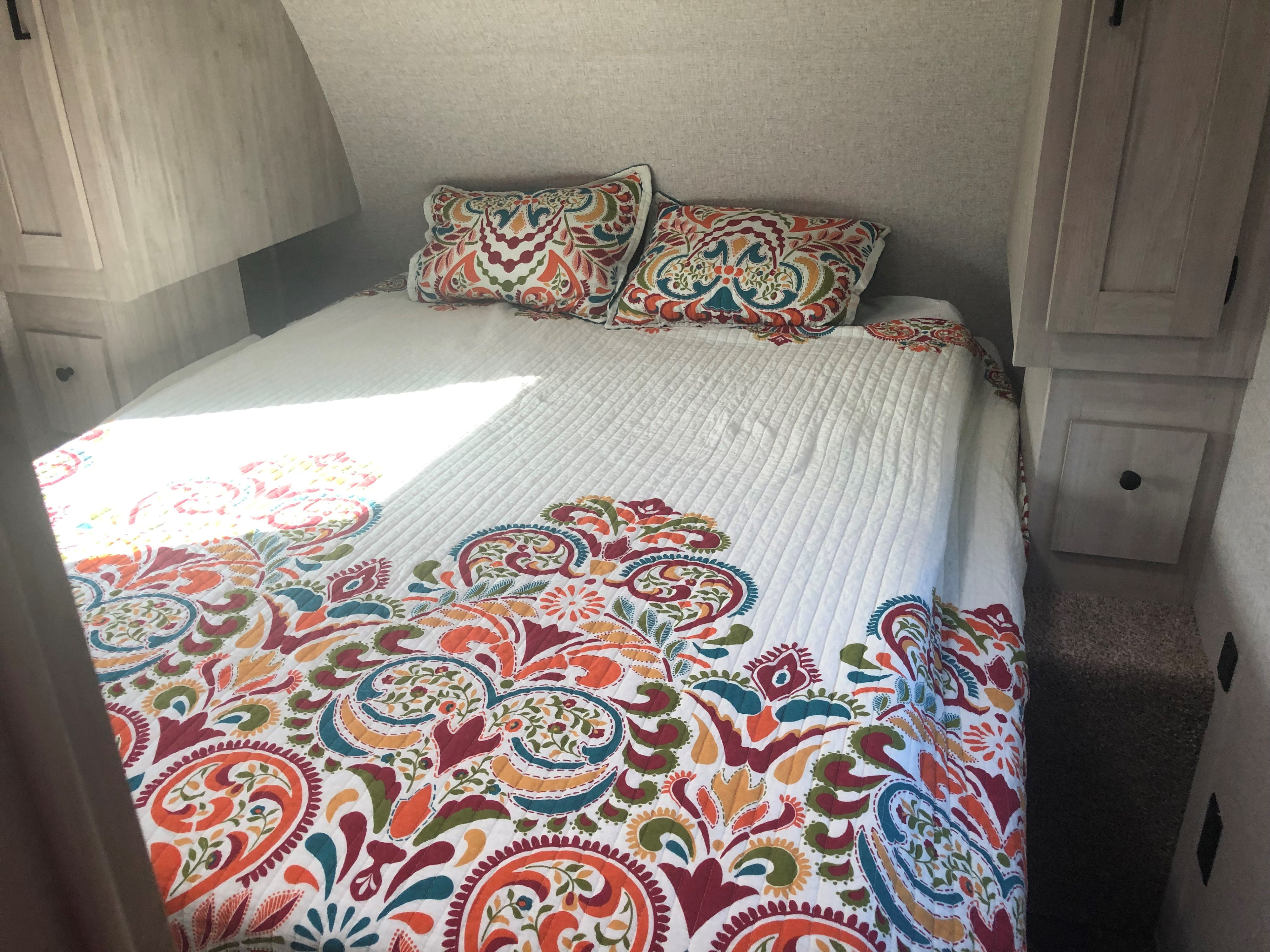 Bright RV rental bedroom with a colorful, patterned quilt and matching pillows on the bed.. East to West Della Terra 2022