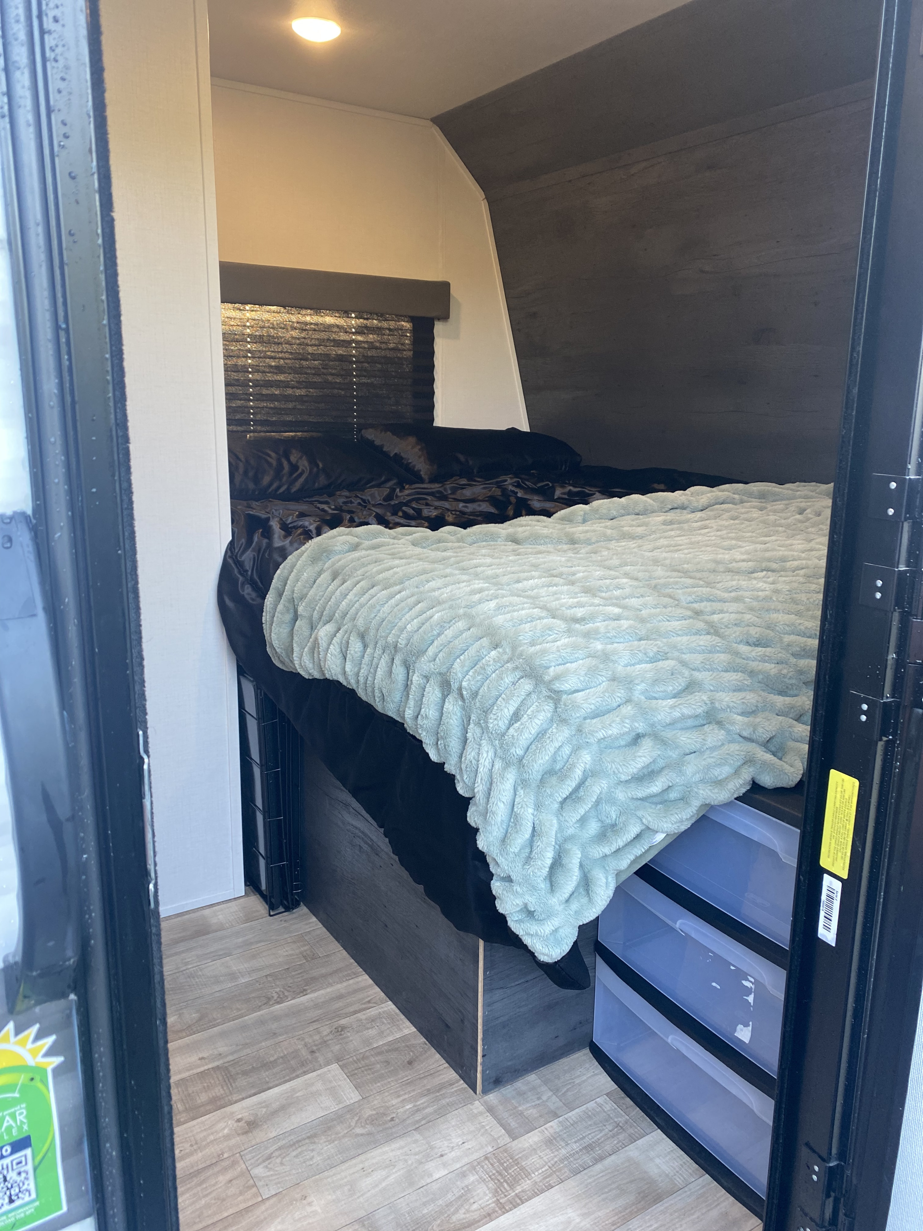 RV rental: A cozy, compact bedroom interior with a bed, plush blue blanket, wood floors, and under-bed storage drawers.. Keystone RV Hideout 2022