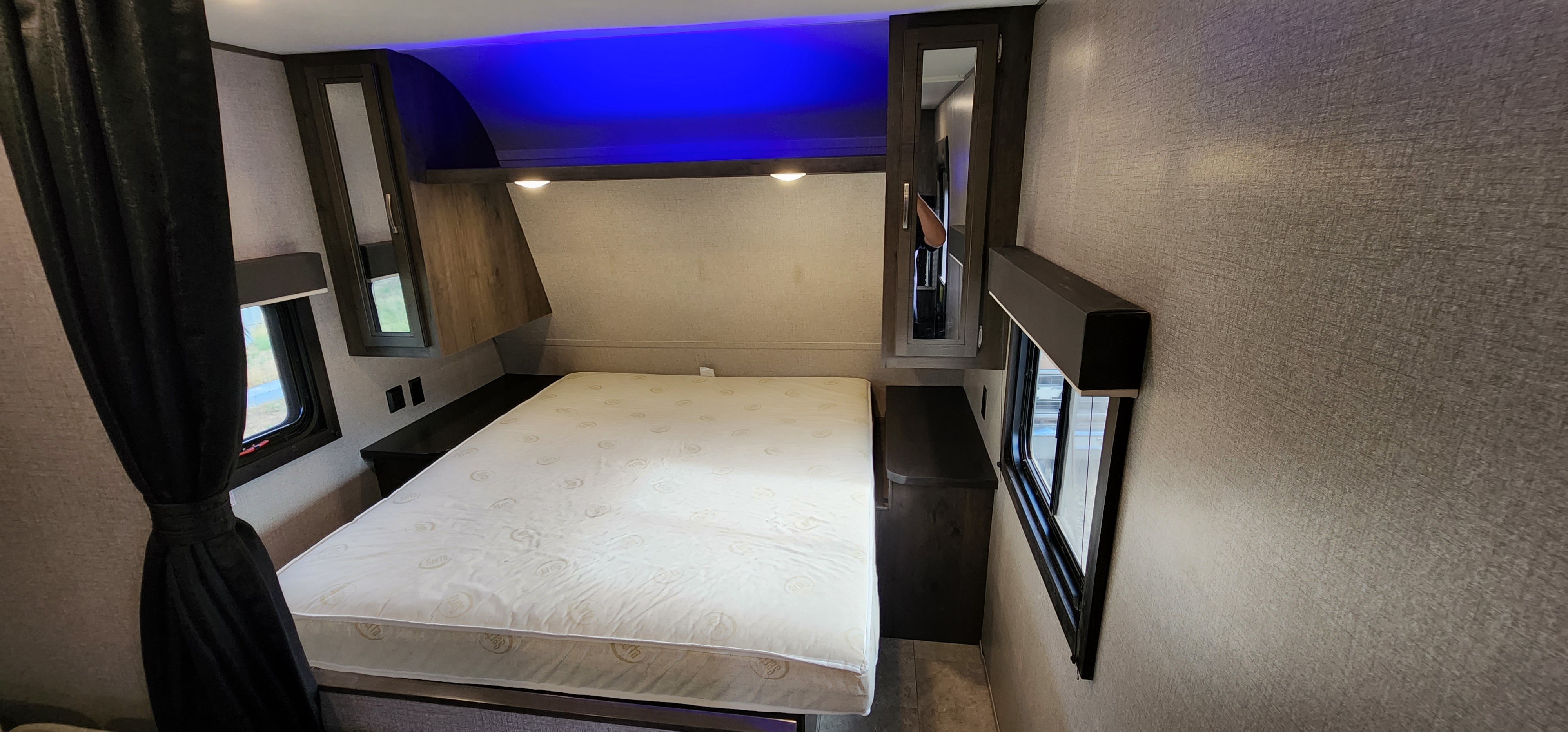 RV rental bedroom: a bed with blue accent lighting, overhead storage, and side windows creating a compact sleeping area.. Jayco Jay Flight SLX 2020