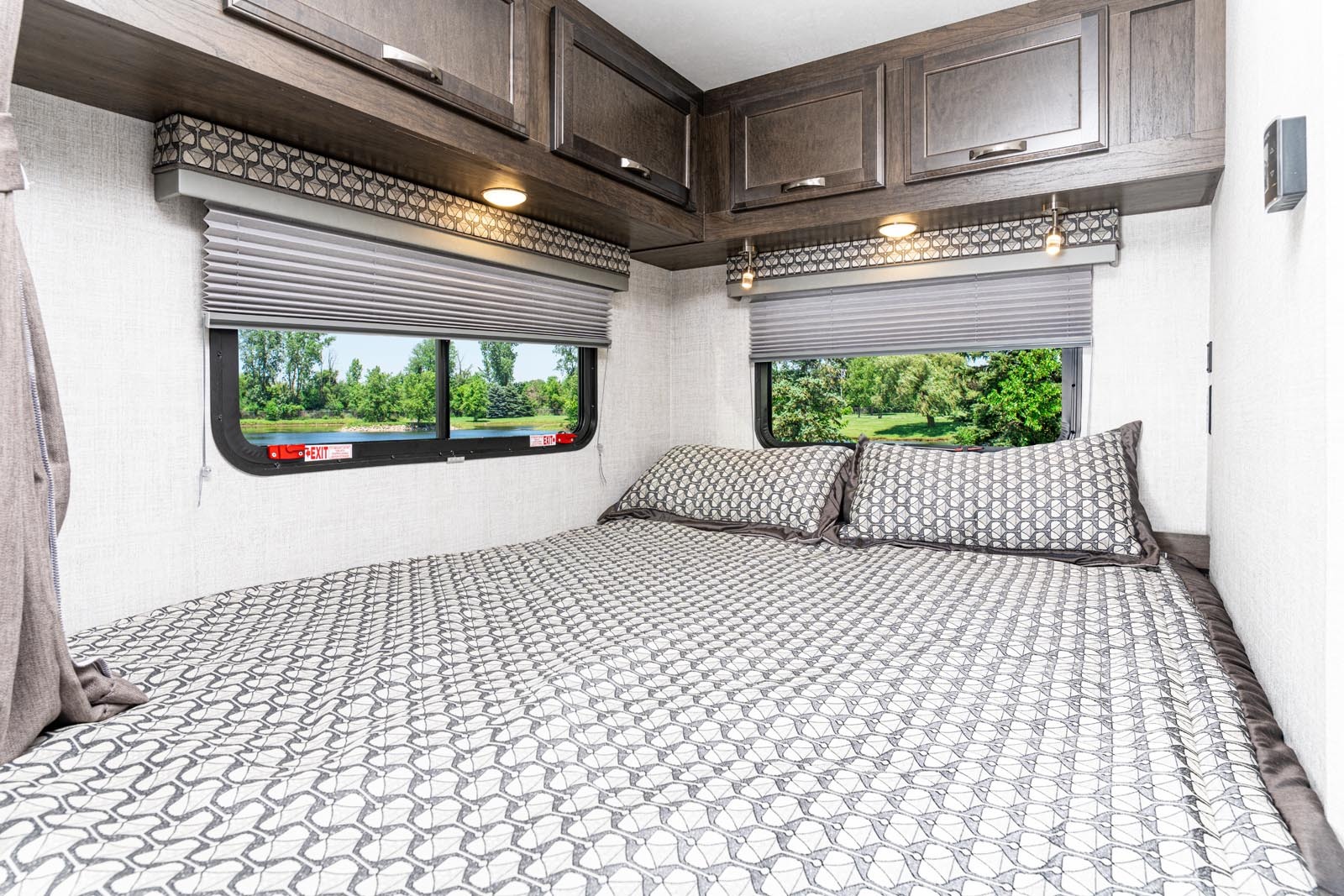 Comfortable RV rental bedroom with a spacious bed, overhead storage, and scenic views from the windows for relaxing travels.. Gulf Stream Conquest 2022