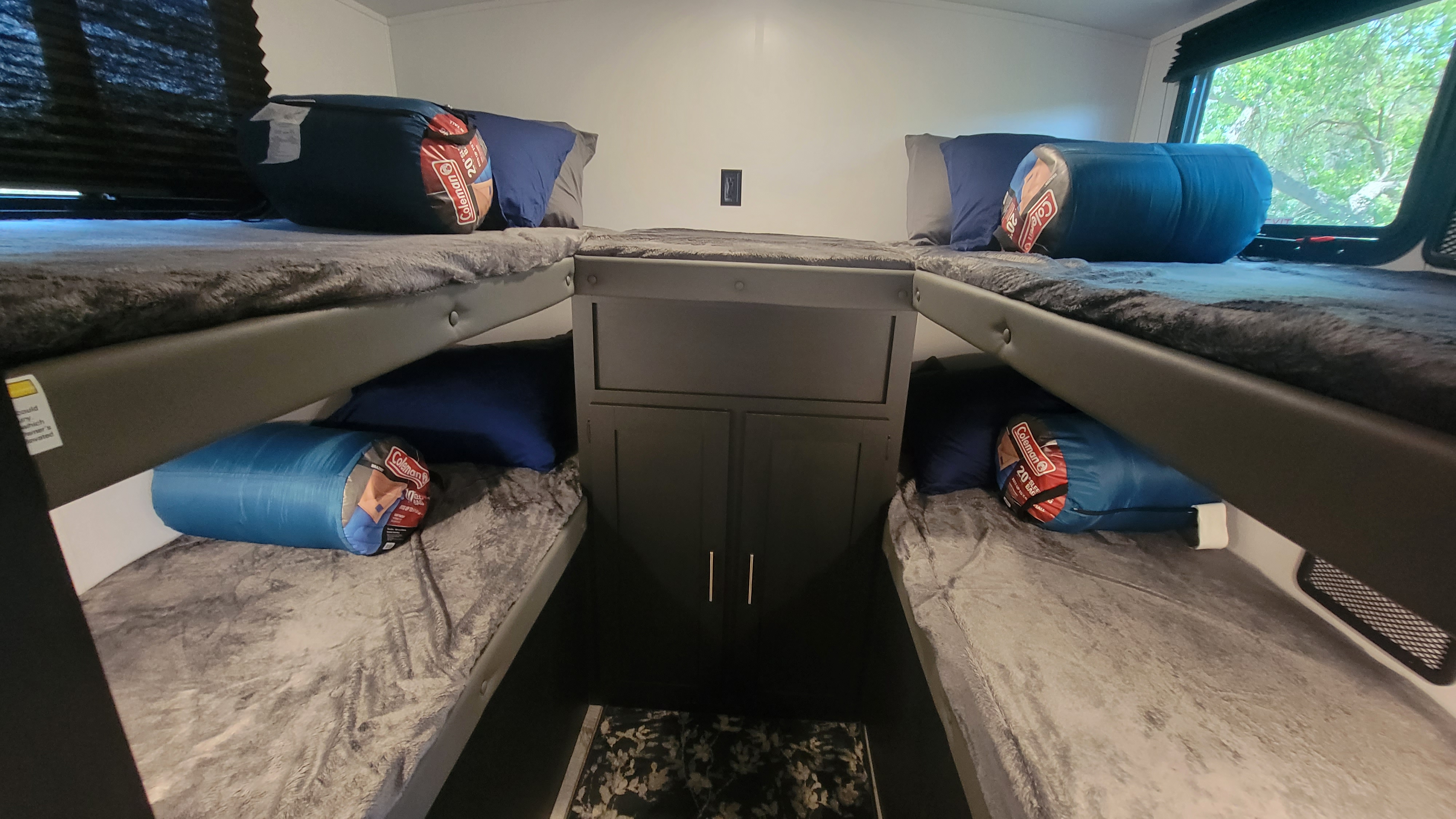 Cozy RV rental sleeping area featuring four bunk beds, each with a pillow and Coleman sleeping bag. Ideal for groups.. Keystone RV Springdale 2022