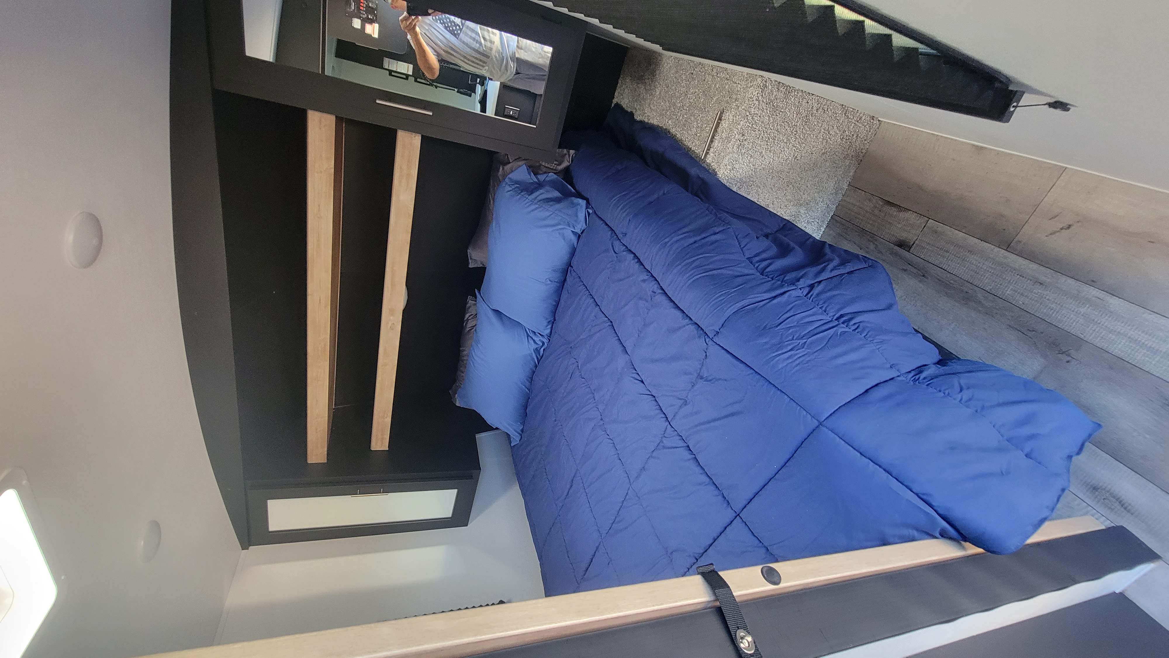 Cozy RV rental bedroom with a blue comforter, mirrored closet, and wood-look flooring. Ready for your adventure!. Keystone RV Springdale 2022