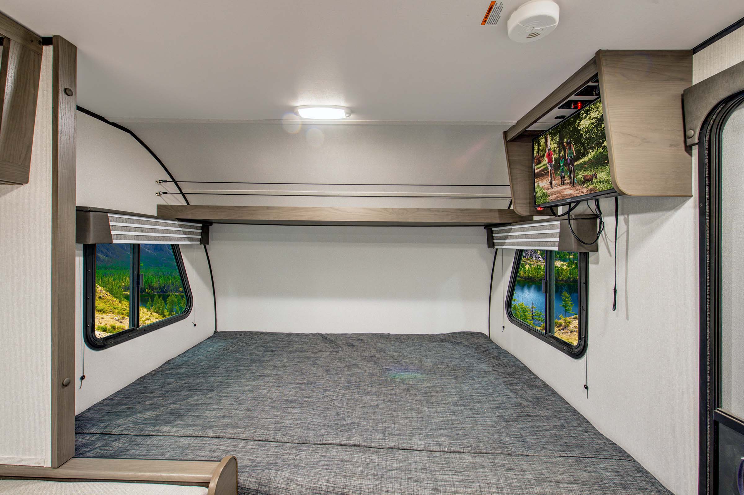 Cozy RV rental bedroom with a comfy bed, scenic windows, and a mounted TV for relaxing after adventures.. Heartland RVs Mallard Pathfinder 2022