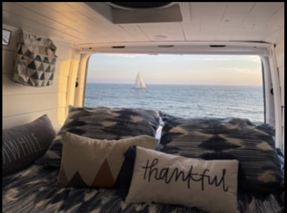 Cozy RV rental interior with bed & pillows. Stunning ocean view from the back, showing a distant sailboat.. Mercedes-Benz Sprinter RV Motorhome Campervan 2016
