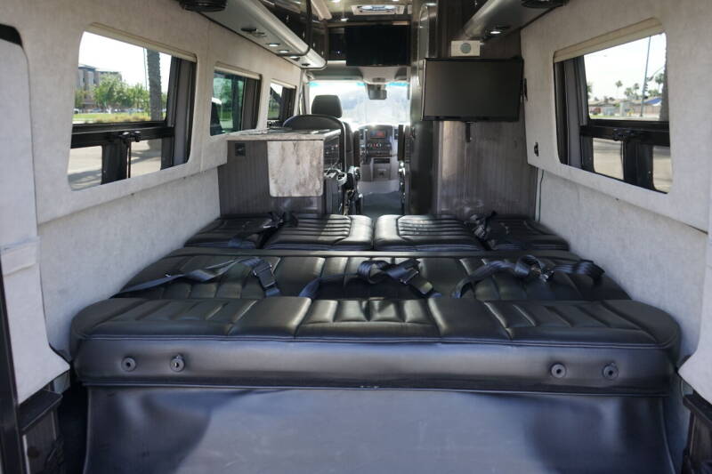 Inside an RV rental: plush black seating, convertible to a large bed, windows, and TV visible. Ideal for road trips.. Airstream Interstate 2016