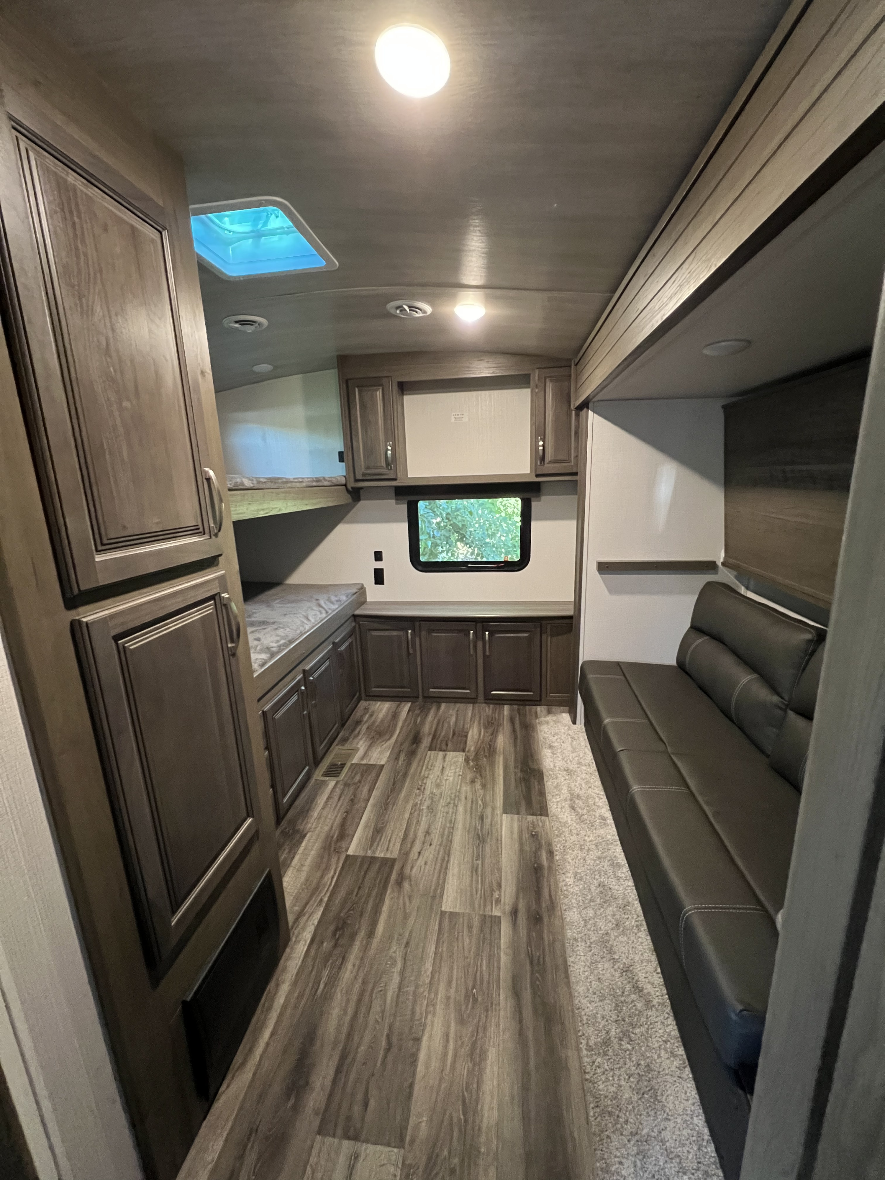 Spacious RV rental interior with bunk beds, abundant storage, and a comfortable sofa, showcasing a modern design.. Keystone RV Cougar 2022