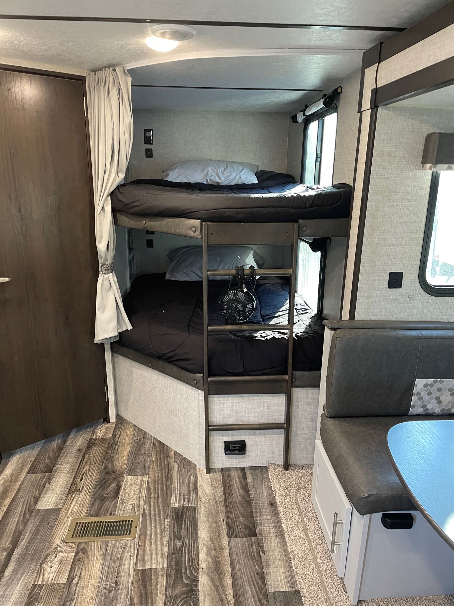 RV rental interior: cozy bunk beds with ladder, dinette seating, and wood-look flooring. Ideal for family adventures.. Keystone Bullet 2020