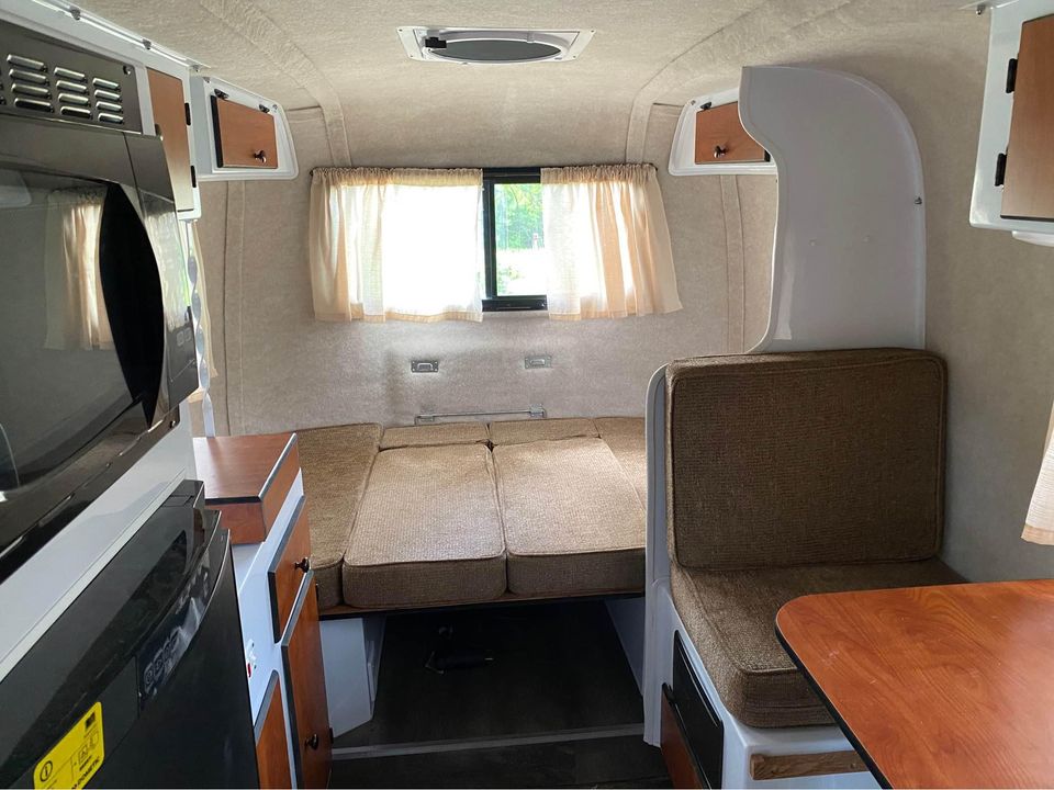 Cozy RV rental interior: visible kitchenette with microwave, overhead cabinets, and a versatile dinette converting to a bed.. Scamp Scamp Trailer 2019