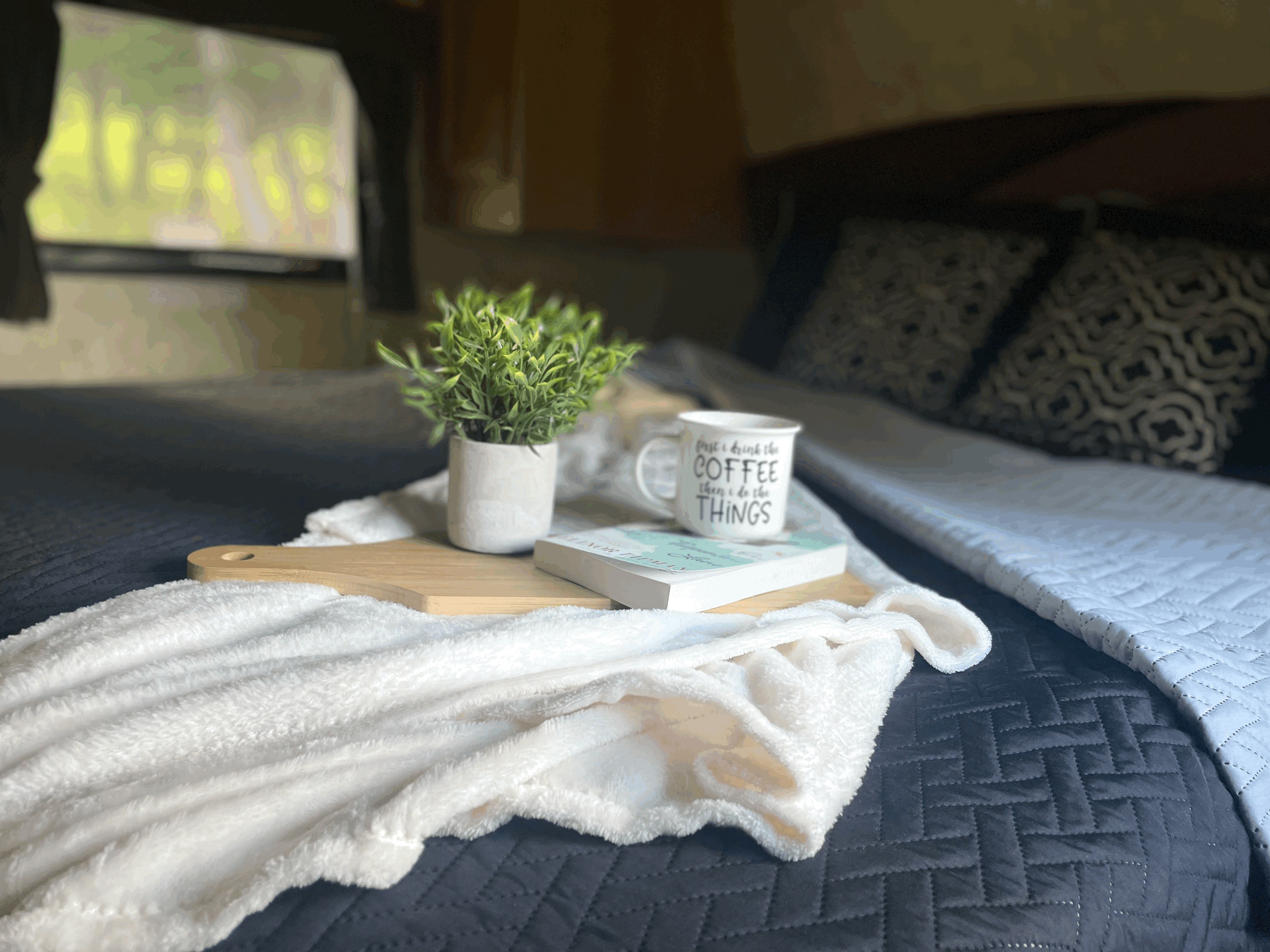 RV rental bed with cozy blanket, book, coffee mug & plant on a tray. Perfect comfort for your travels.. Jayco Jay Flight 2009