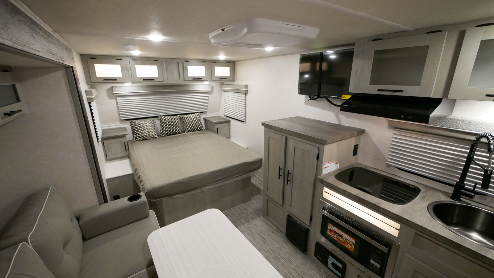Well-equipped RV rental interior features a compact kitchen, comfortable bed, and living area, ideal for mobile adventures.. Forest River 19QBS 2022