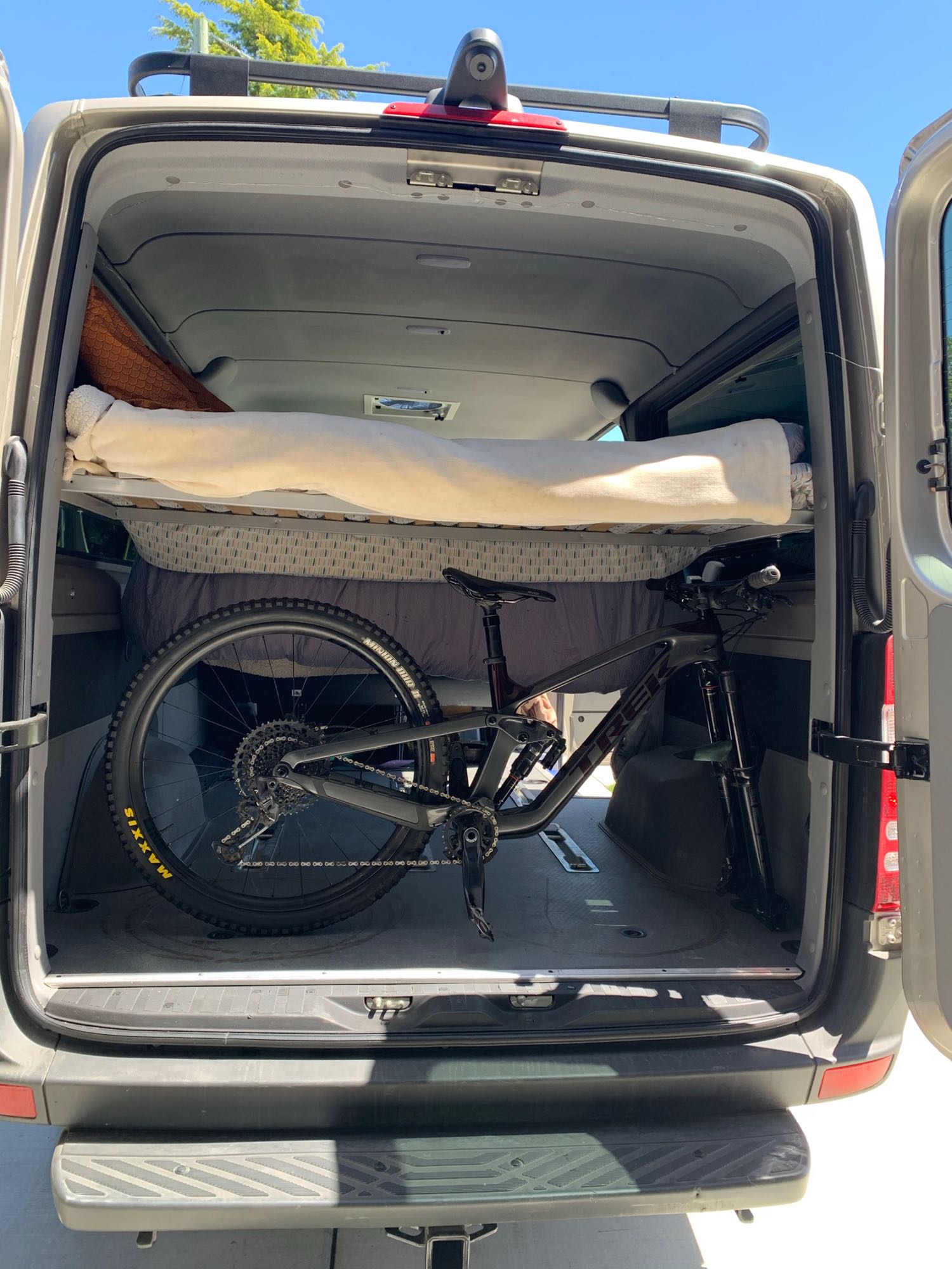 Inside an RV rental van, a mountain bike is stored under a raised bed. Ideal for adventure travel.. Mercedes-Benz Sprinter 2018