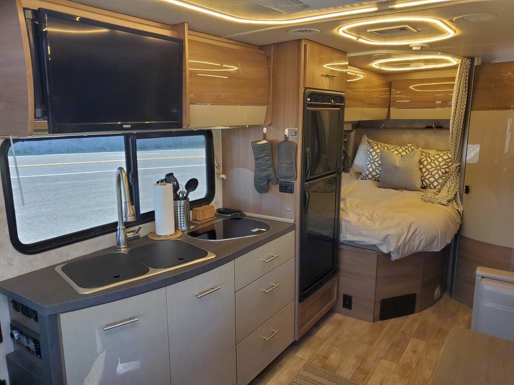 RV rental interior: well-appointed kitchen with sink & TV, fridge, and a comfortable bedroom. Perfect for road trips.. Winnebago View 2018