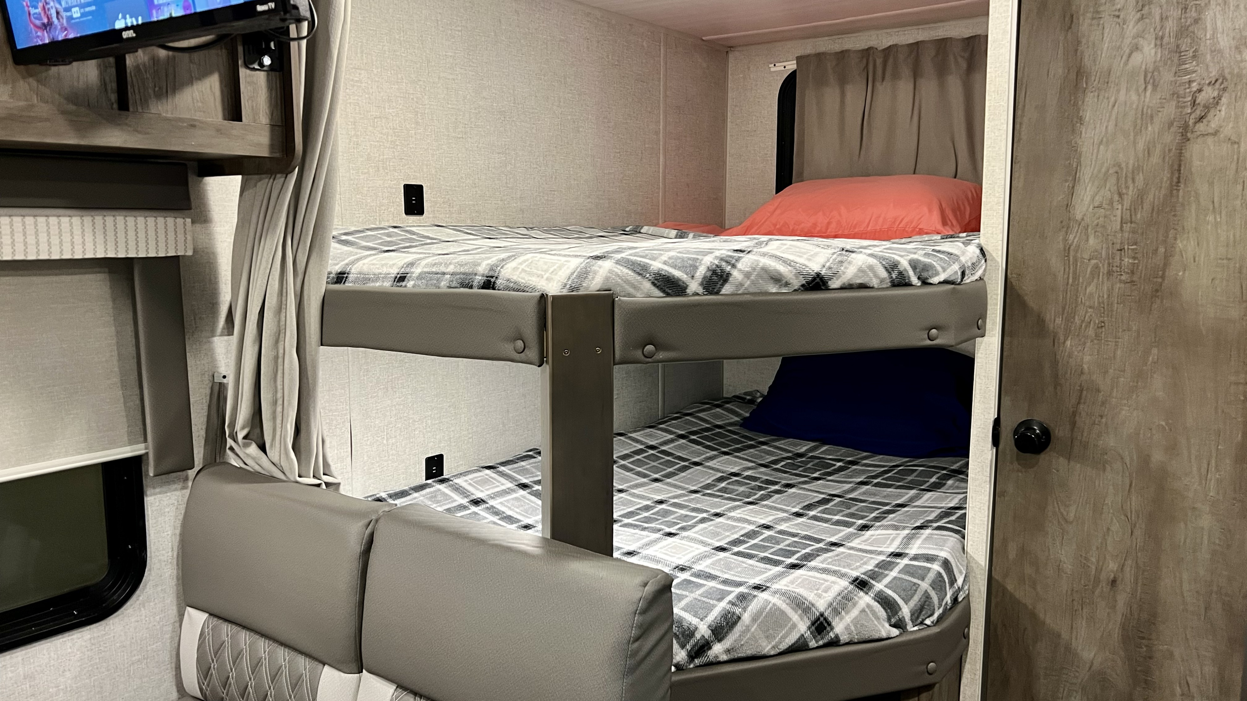 RV rental interior: cozy bunk beds with plaid blankets, a comfy seating area, and practical USB ports.. Forest River Wildwood X-Lite 2021
