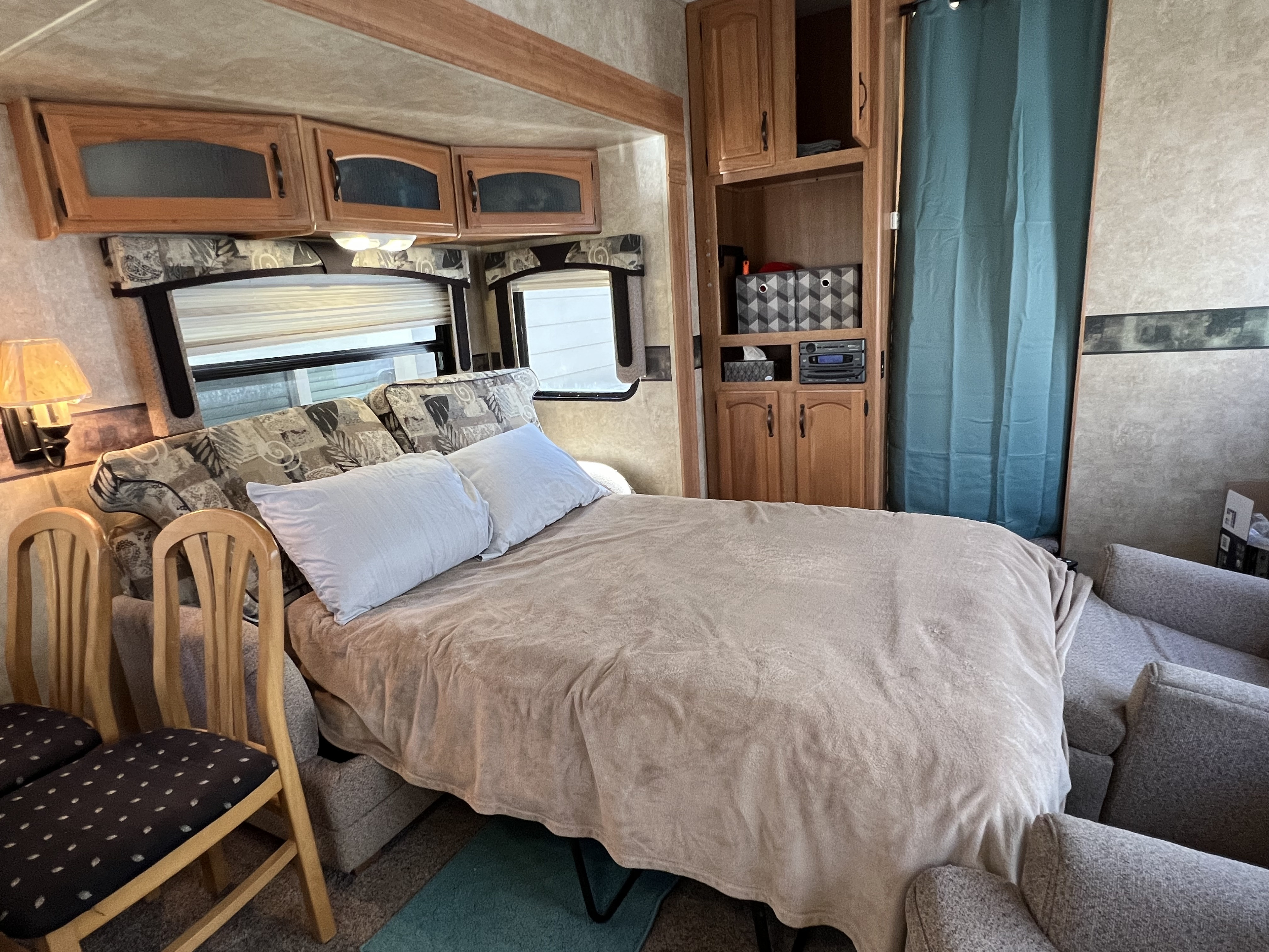 This RV rental interior features a cozy bed, wood cabinets, and integrated storage, making it a functional living space.. Keystone RV Copper Canyon 2008