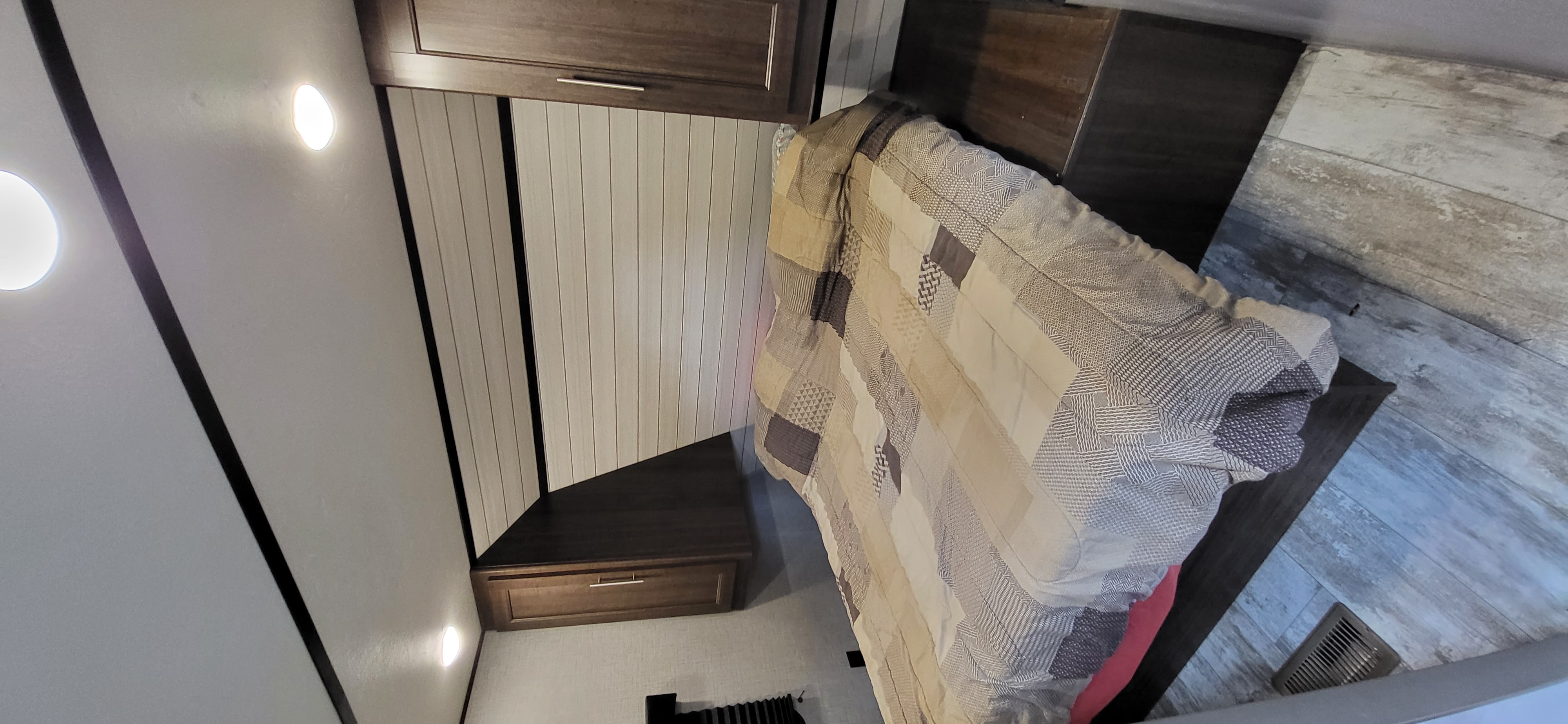 RV rental bedroom showcasing a patterned bedspread, overhead cabinets, and wood-look flooring. Bright and inviting.. Crossroads RV Zinger Lite 2020