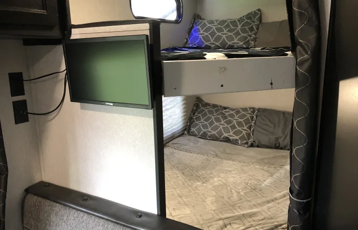 RV rental interior featuring bunk beds with patterned bedding and a wall-mounted TV.. Forest River Cherokee Grey Wolf Special Edition 2021