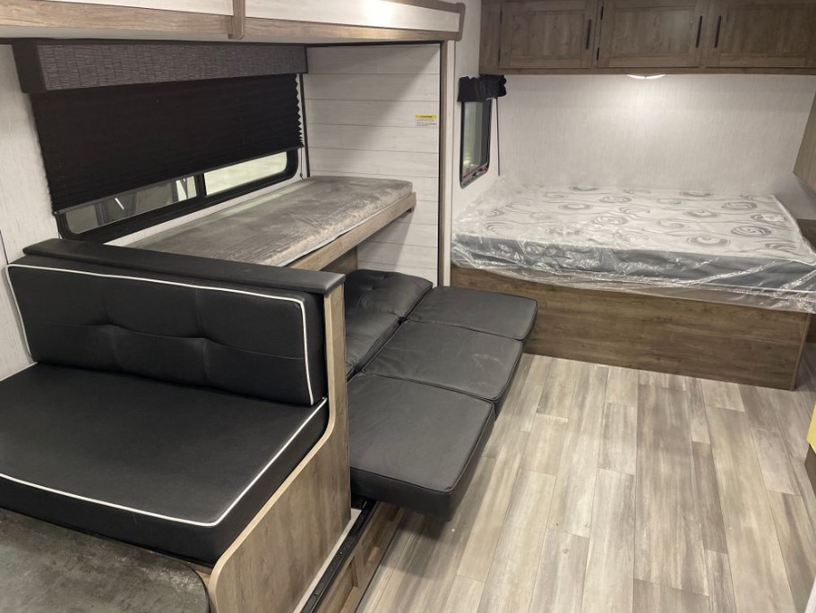 RV rental interior featuring bunk beds, a converting sofa, and a main bed with a covered mattress.. Heartland RVs Pioneer Trail Blazer 2022