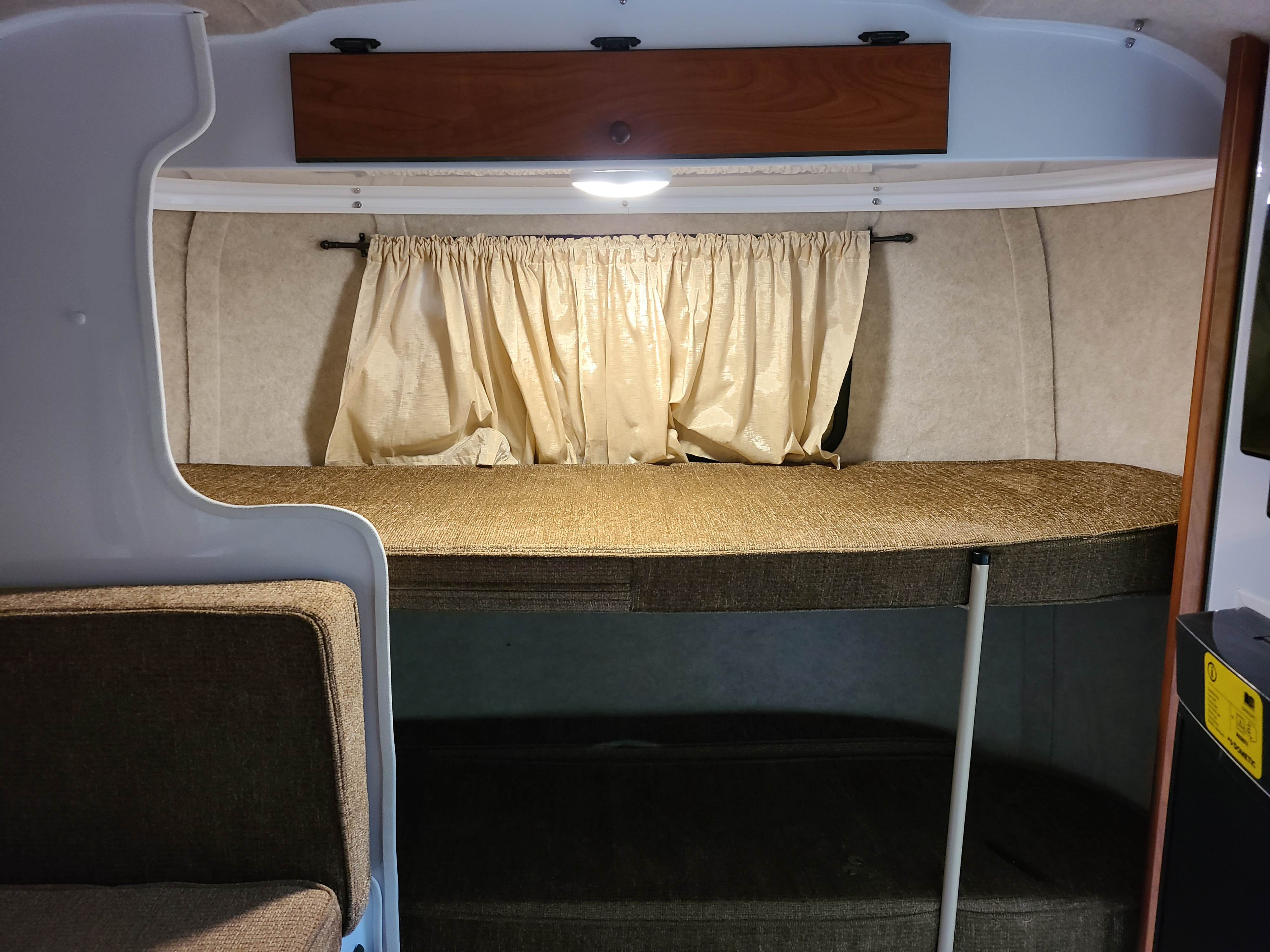 Cozy RV rental interior with bunk beds, curtains, and overhead storage, designed for compact living.. Scamp Scamp Trailer 2019