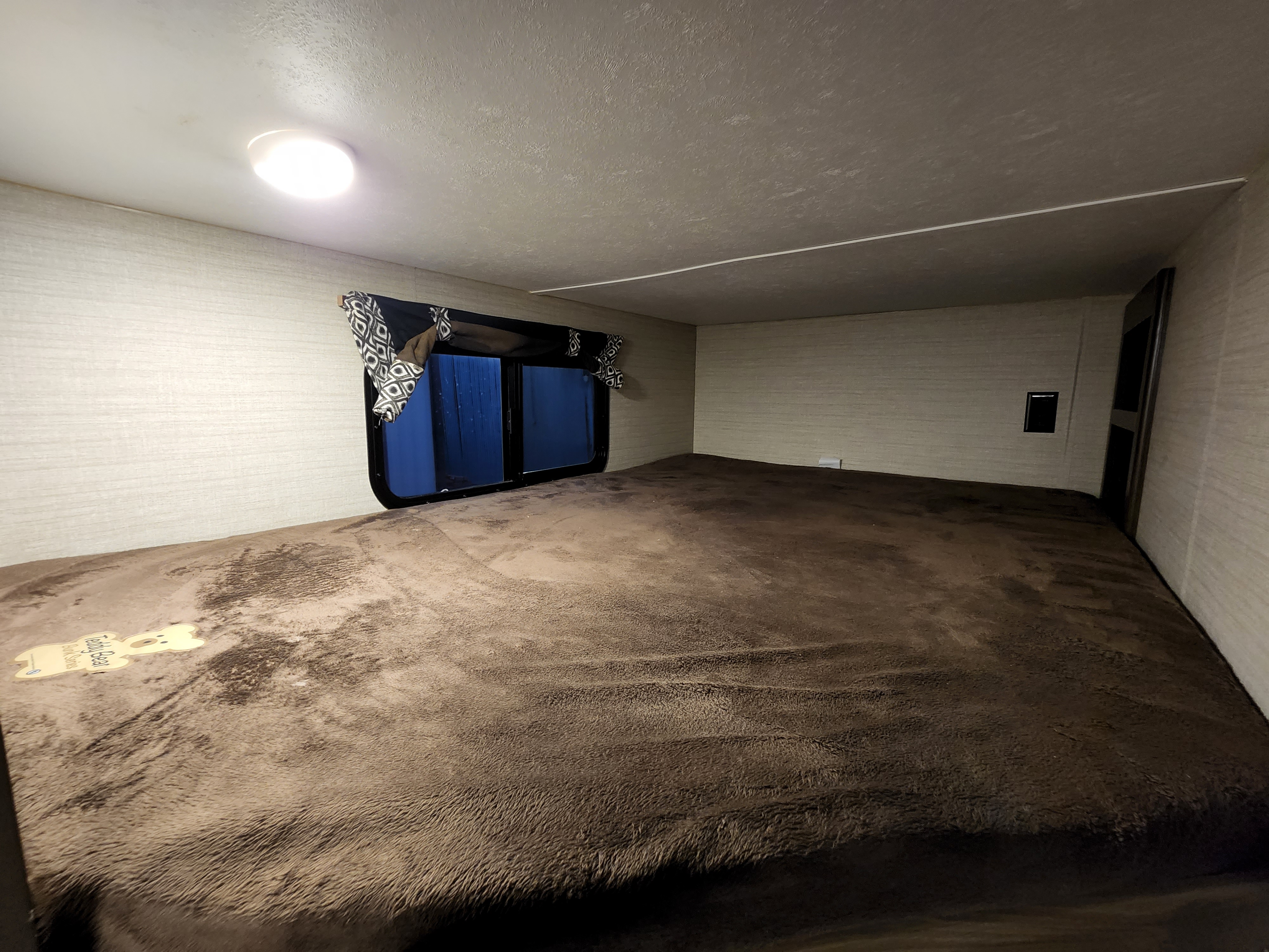 Cozy RV rental sleeping area with soft brown blanket and window. Perfect for your next adventure.. Keystone Bullet 2017