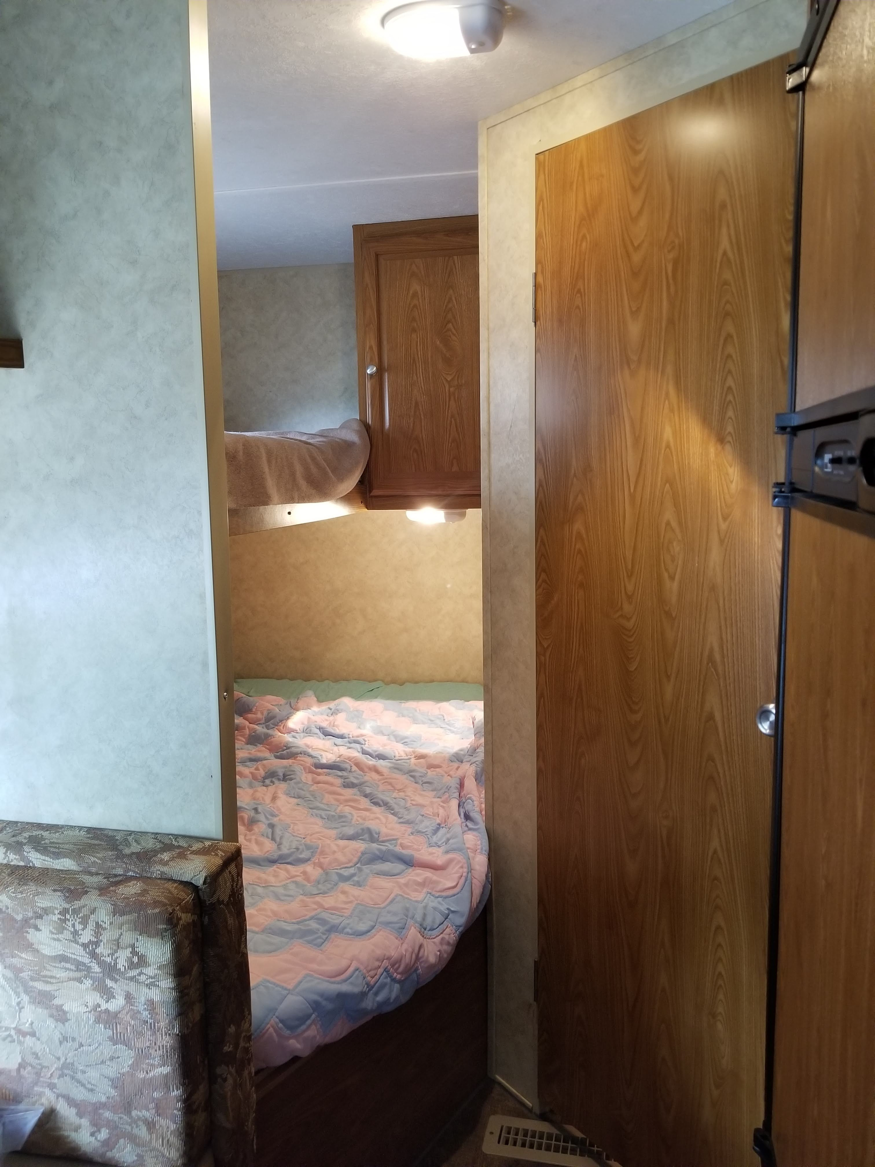 This RV rental features a hallway leading to cozy bunk beds, complete with wood cabinets and bright overhead lighting.. Dutchmen Sport Lite 2009