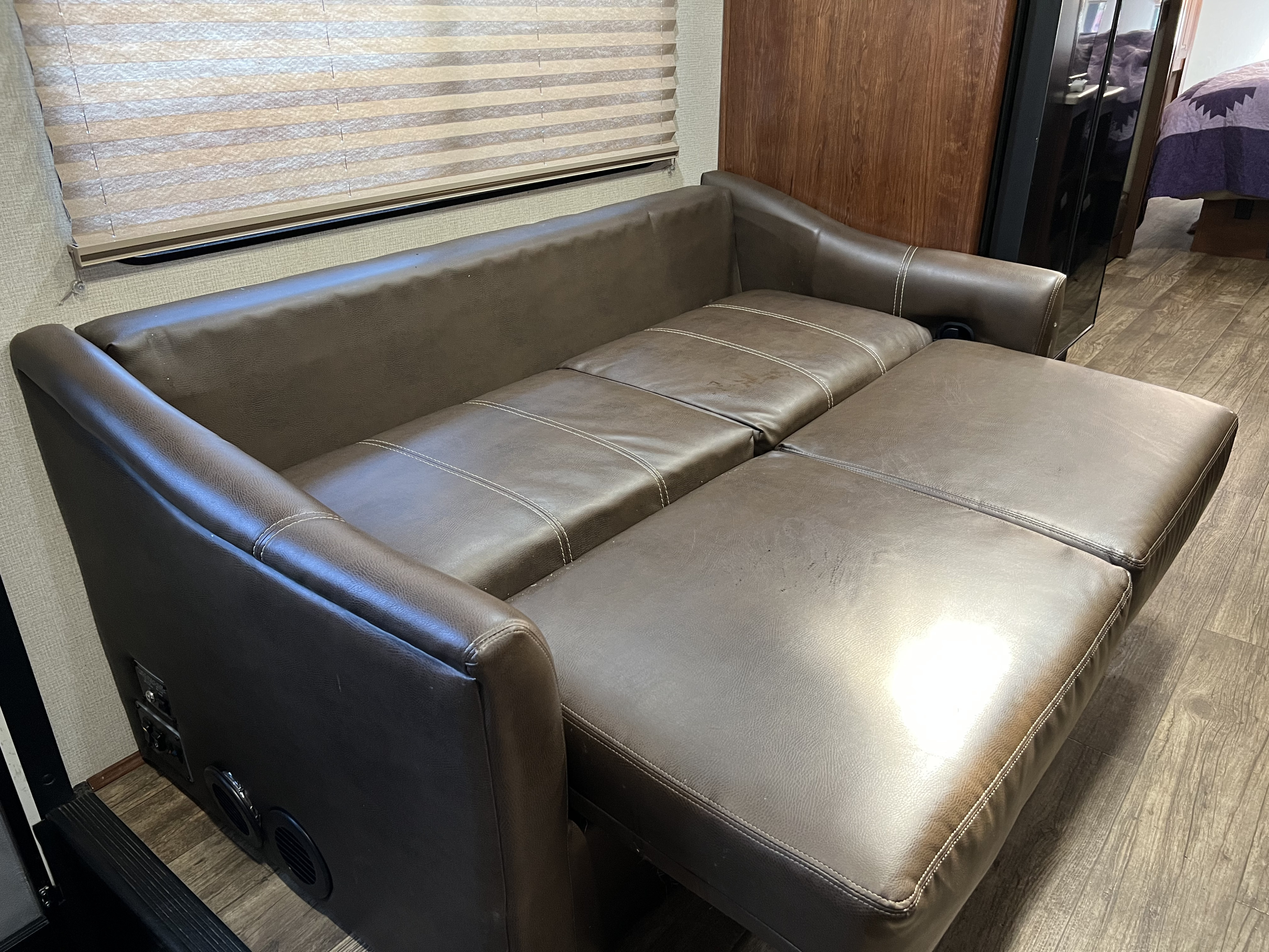 RV rental: Brown leather sofa bed, partially extended, inside an RV with wood-look flooring and pleated window blinds.. Other Other 2018