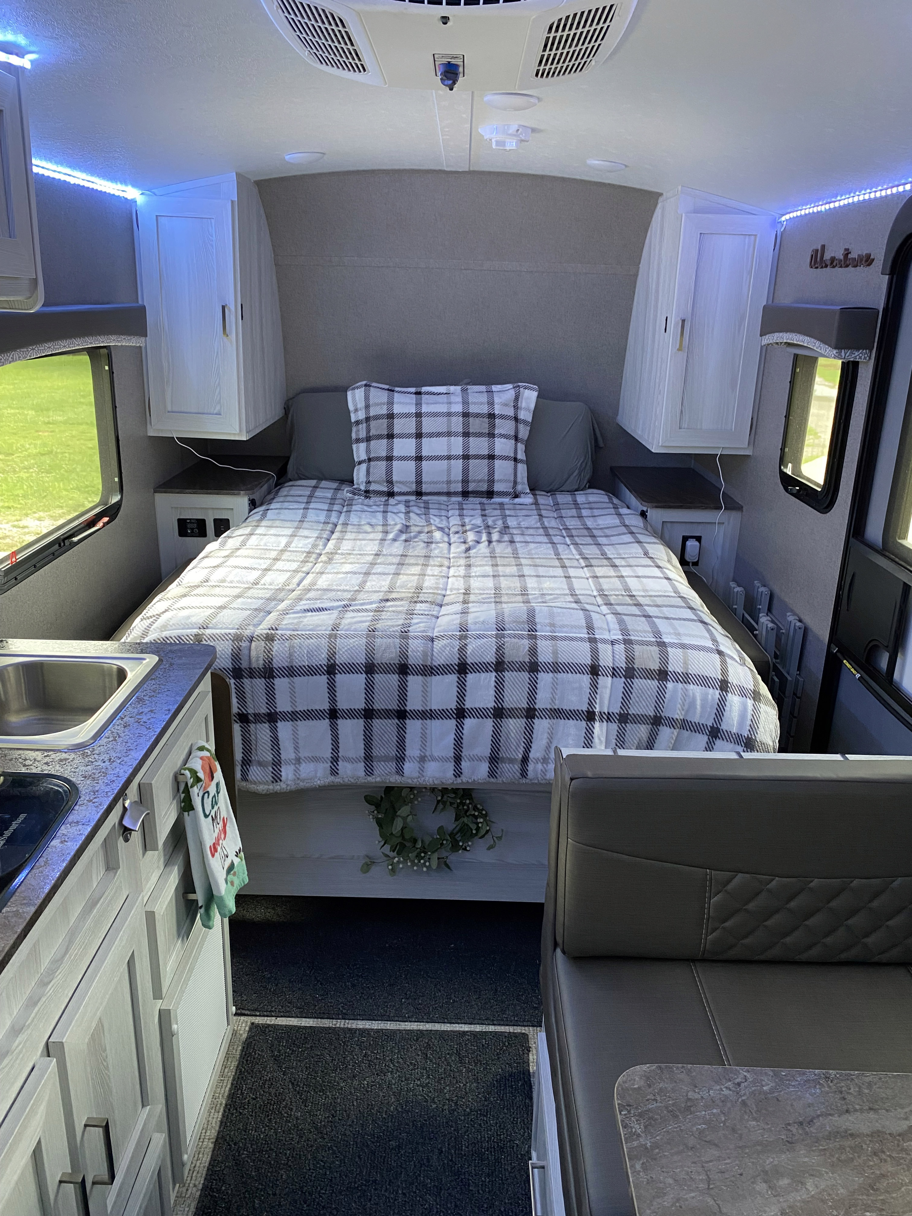 Cozy RV rental interior featuring a plaid bed, kitchen area, and dinette. Blue LED lights add ambiance.. Forest River Rockwood 2020